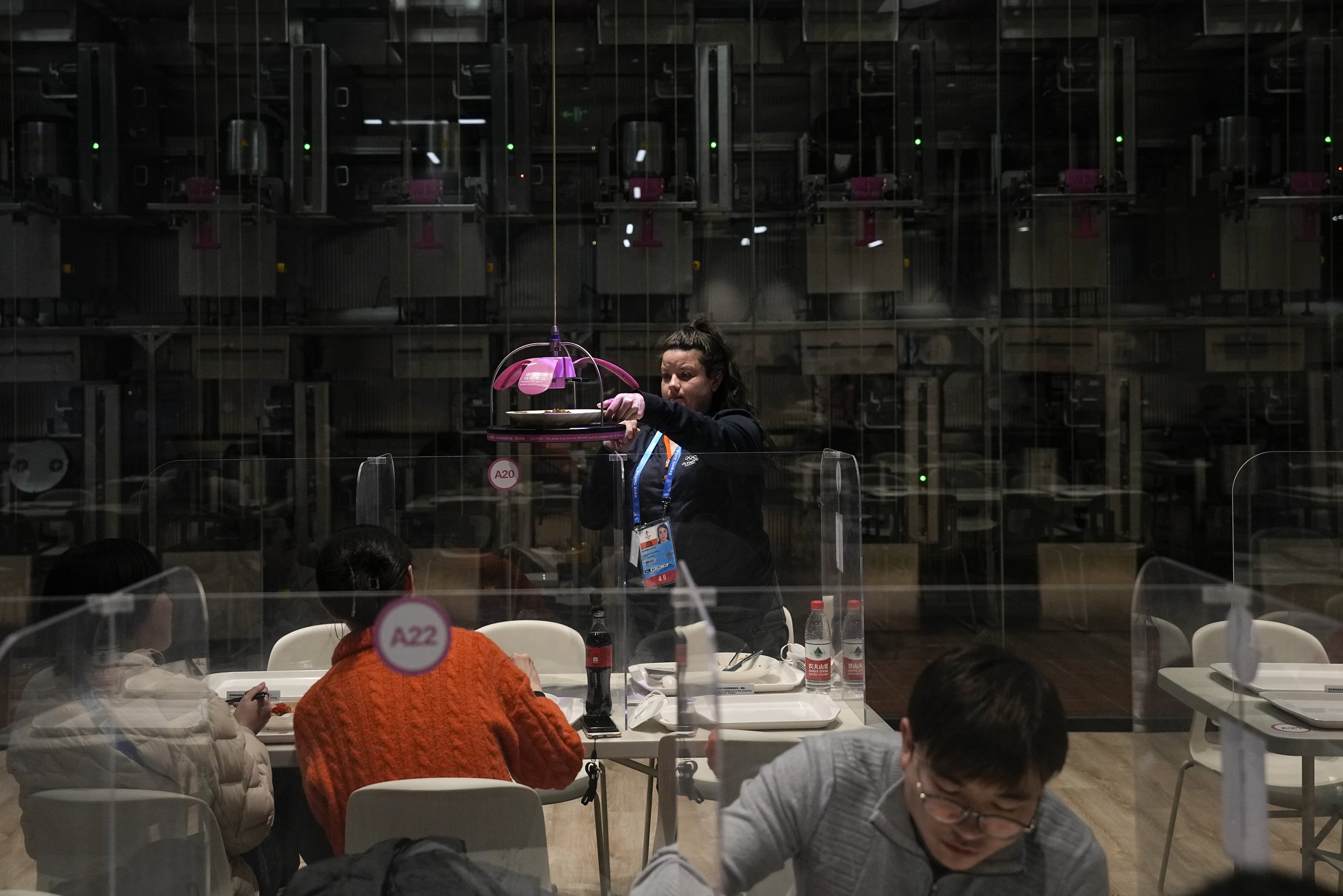  A woman grabs her lunch delivered to her robotically in the media dining area of the main media center ahead of the 2022 Winter Olympics, Wednesday, Feb. 2, 2022, in Beijing. (AP Photo/Jae C. Hong) 