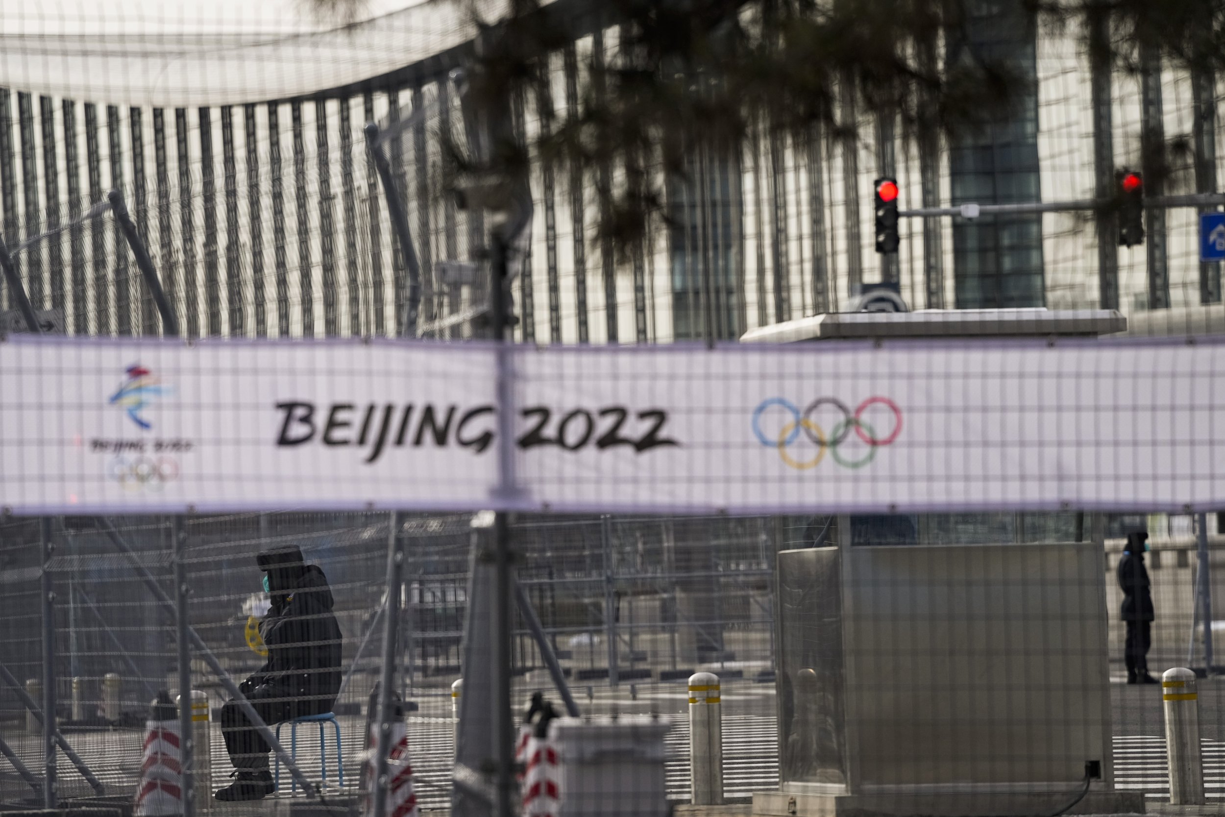  Two security personnel are seen through fences outside the main media center at the 2022 Winter Olympics, Wednesday, Jan. 26, 2022, in Beijing. (AP Photo/Jae C. Hong) 