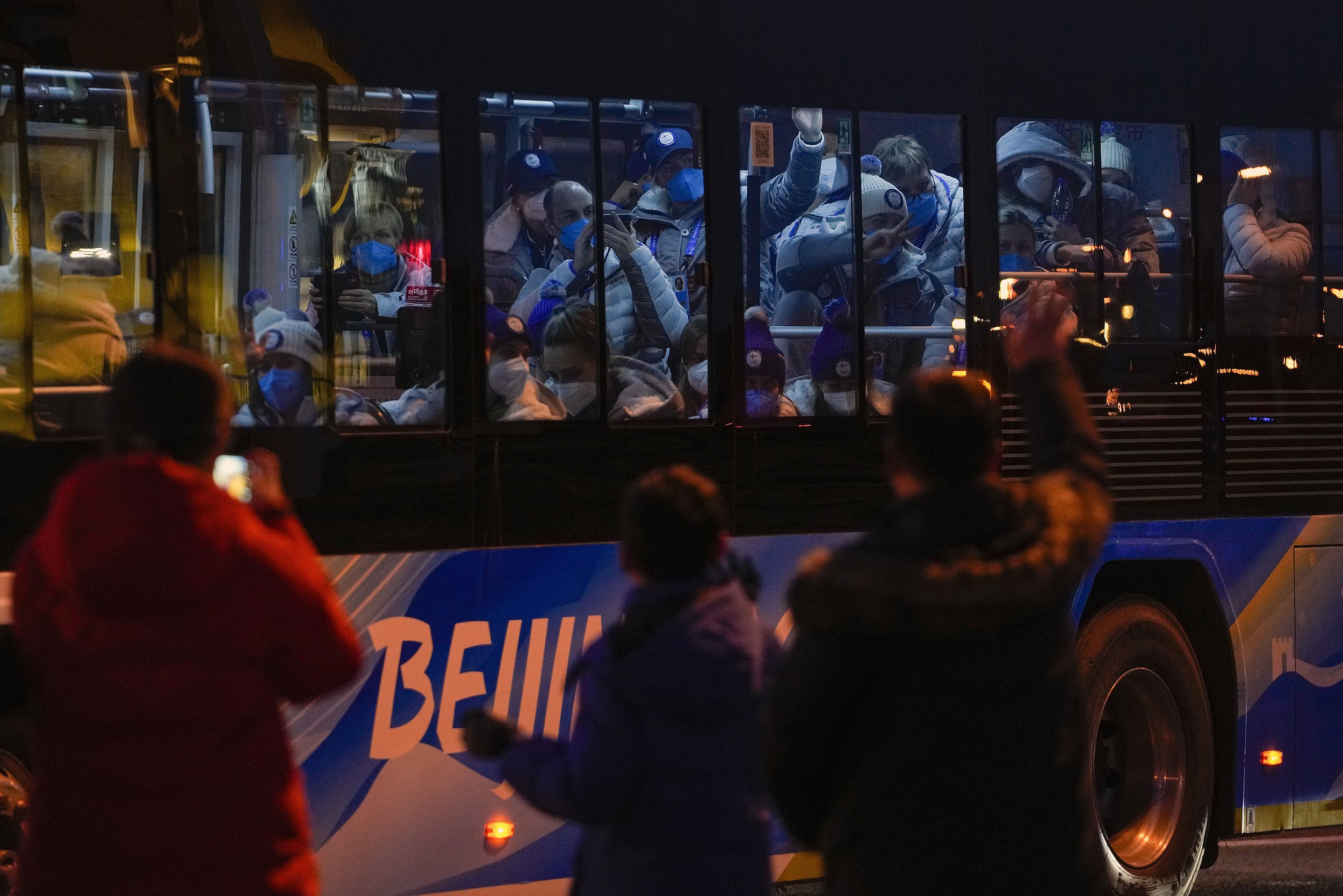  Foreign athletes inside a bus respond to residents on a street as they were heading to the National Stadium ahead of the opening ceremony of the 2022 Winter Olympics, in Beijing, Feb. 4, 2022. (AP Photo/Andy Wong) 