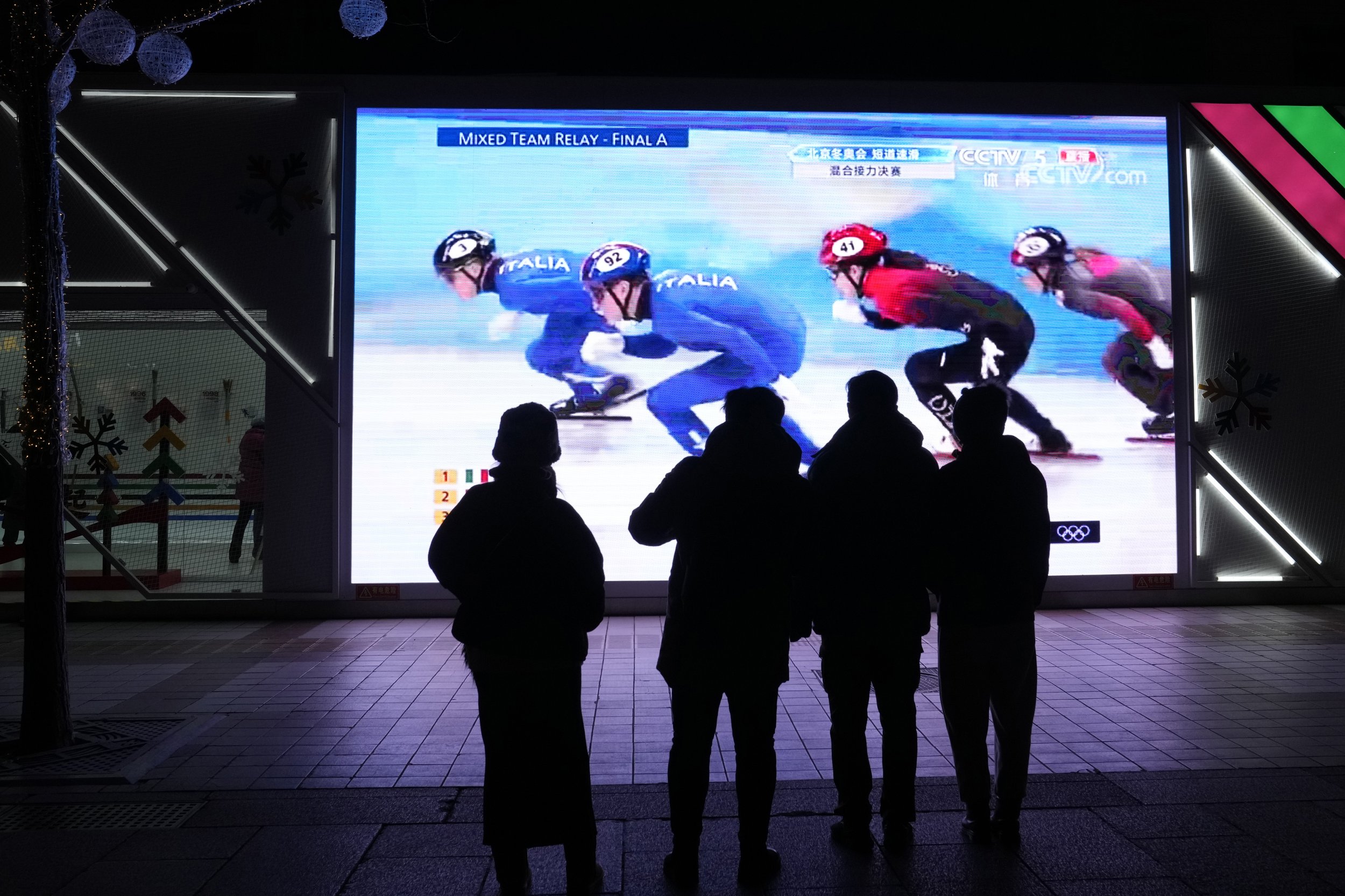  Residents watch a big screen showing China's team in the mixed team relay final during the short track speedskating competition at the 2022 Winter Olympics in Beijing, China, Saturday, Feb. 5, 2022. (AP Photo/Ng Han Guan) 