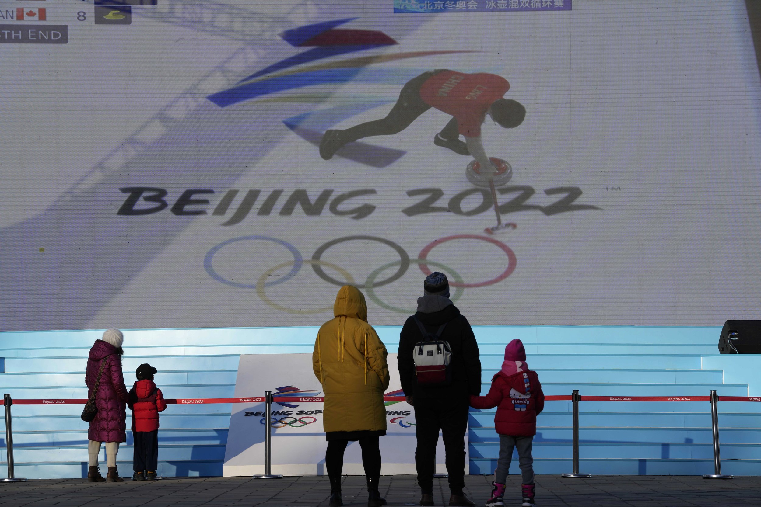  Residents watch a broadcast of a curling competition for the 2022 Winter Olympics shown on a big screen at a special site set up for the public in Beijing, China, Saturday, Feb. 5, 2022, in Beijing. (AP Photo/Ng Han Guan) 