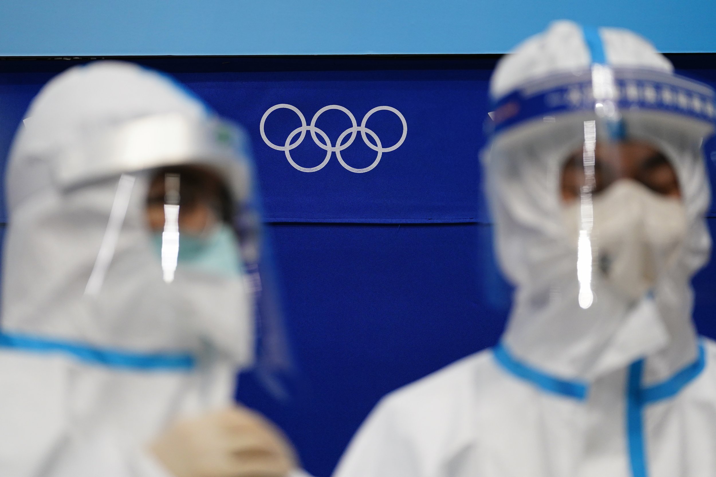  The Olympic rings are seen behind workers staged in protective equipment at the National Indoor Stadium at the 2022 Winter Olympics, Tuesday, Feb. 1, 2022, in Beijing. (AP Photo/Matt Slocum) 