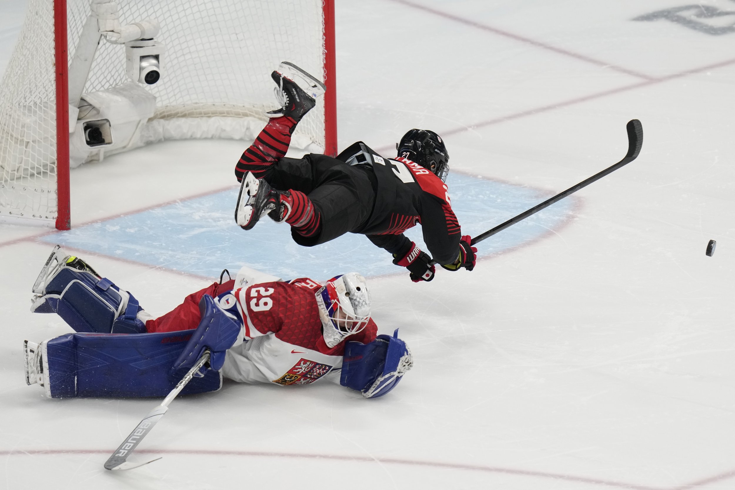  Japan's Remi Koyama (27) flips over Czech Republic goalkeeper Klara Peslarova (29) during a failed shoot-out attempt during a preliminary round women's hockey game at the 2022 Winter Olympics, Tuesday, Feb. 8, 2022, in Beijing. (AP Photo/Petr David 