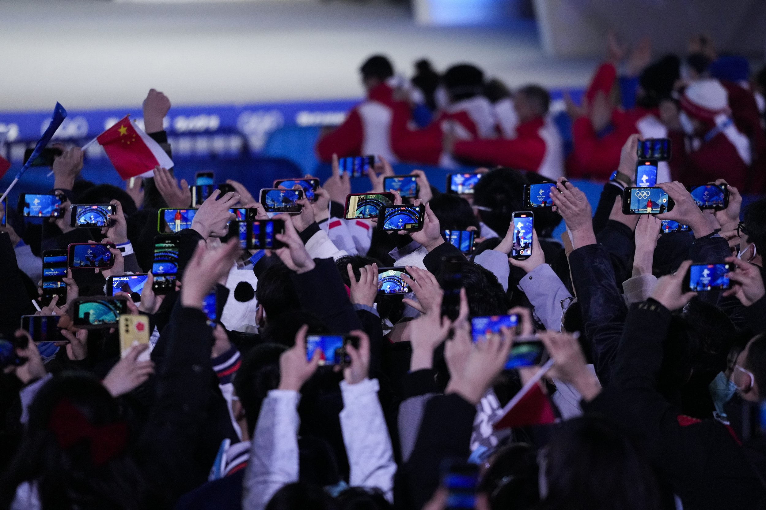  Olympic workers and volunteers hold up their smartphones to record a medal ceremony for the women's freestyle skiing big air at the 2022 Winter Olympics, Tuesday, Feb. 8, 2022, in Beijing. (AP Photo/Jae C. Hong) 