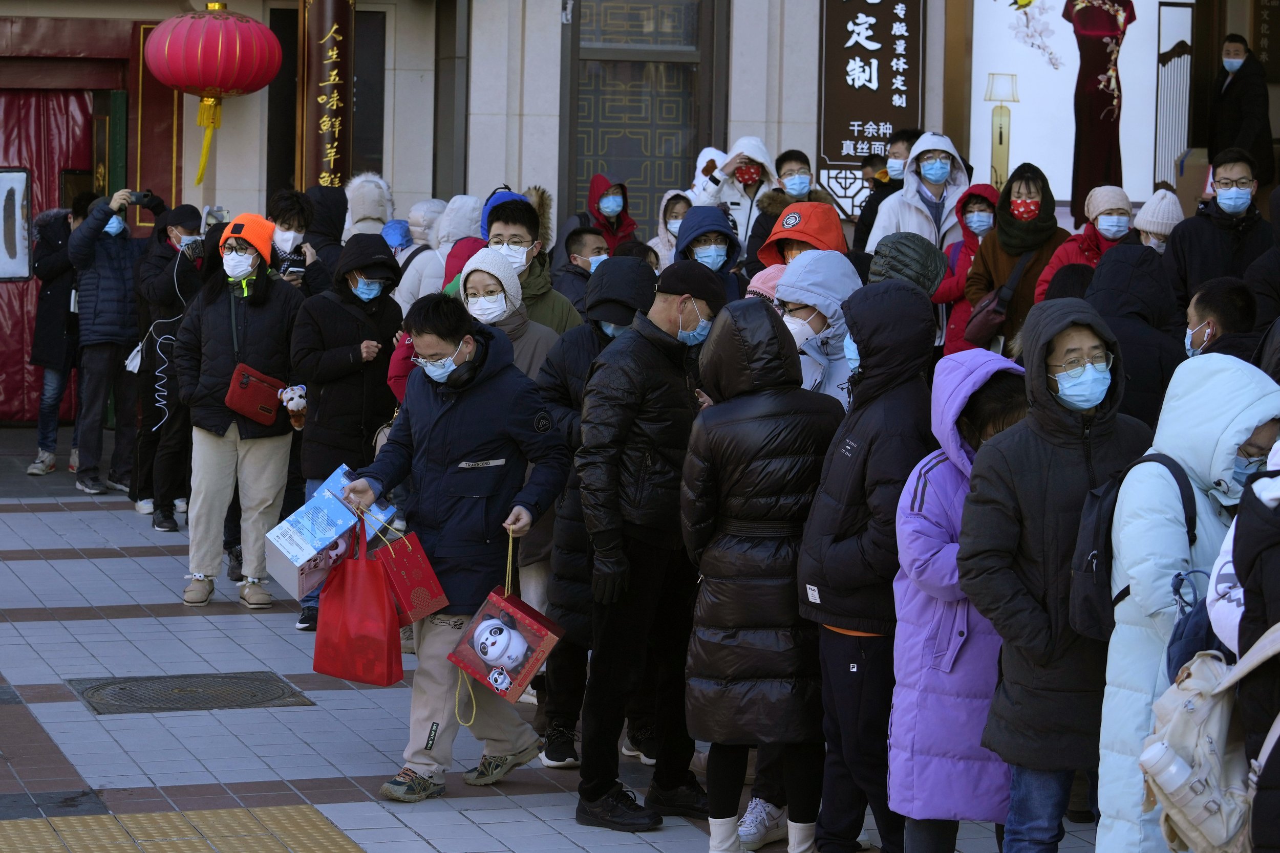  A resident carries away his purchase of 2022 Winter Olympics memorabilia including  mascot Bing Dwen Dwen after lining up outside a store in Beijing, China, Friday, Feb. 4, 2022. (AP Photo/Ng Han Guan) 
