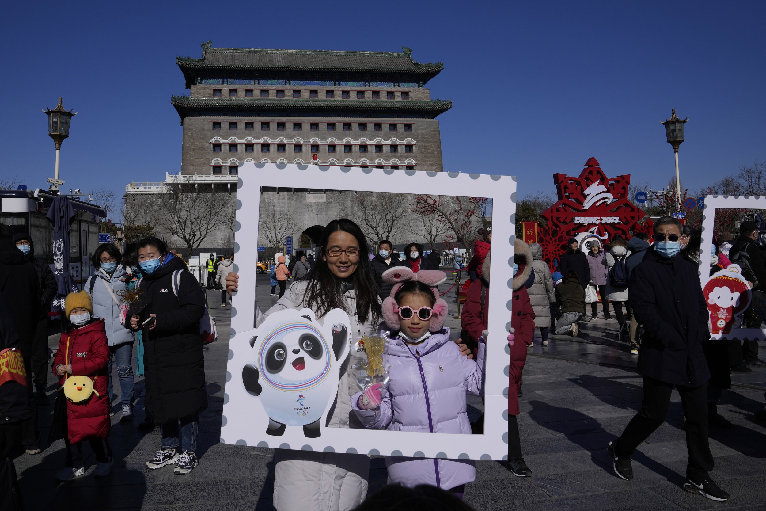  Residents pose for photos with a cutout showing the Olympic mascot Bing Dwen Dwen at a popular retail street in Beijing, China, Friday, Feb. 4, 2022. (AP Photo/Ng Han Guan) 