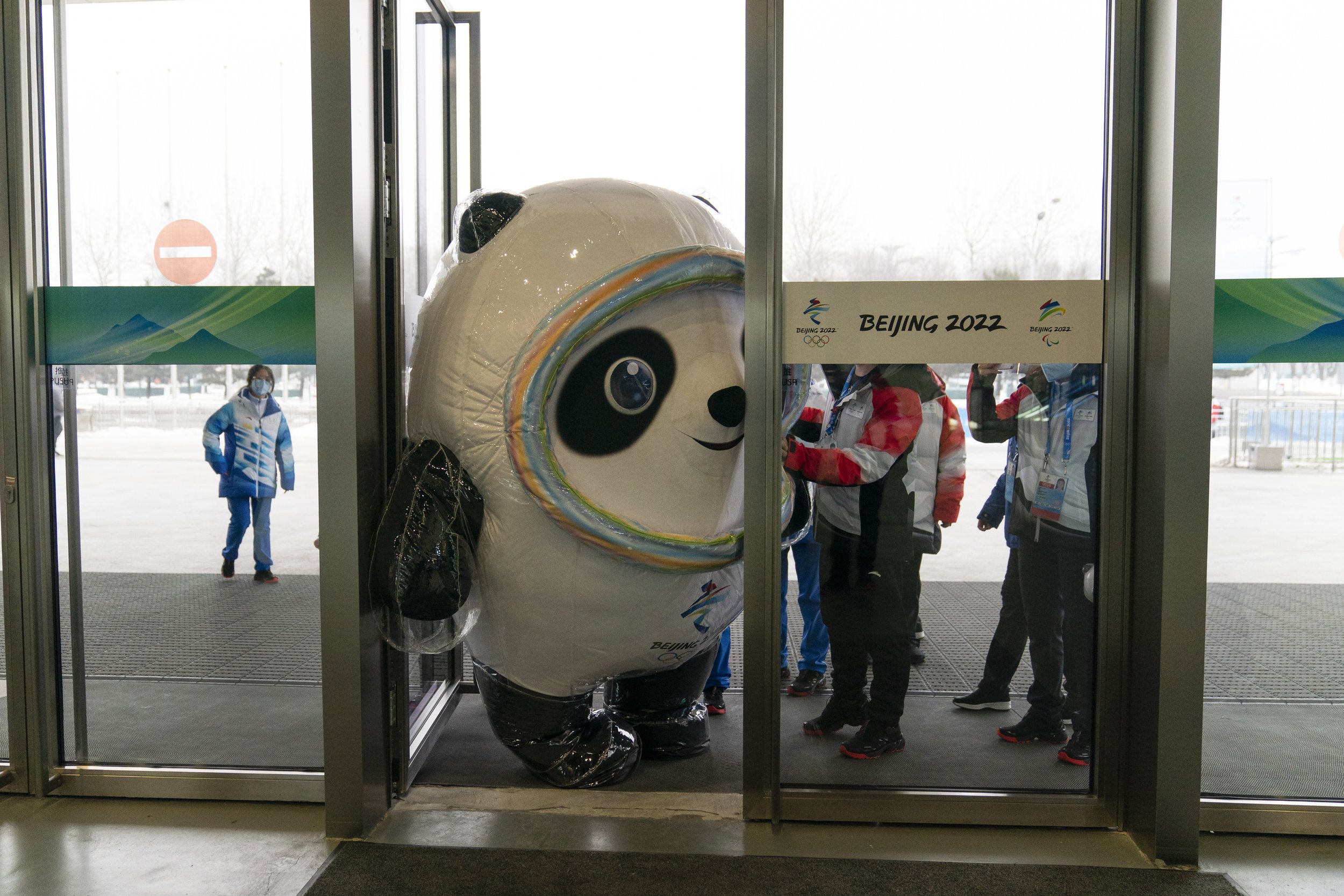  Olympic mascot, Bing Dwen Dwen, tries to squeeze through the door to enter the main media center at the 2022 Winter Olympics, Jan. 24, 2022, in Beijing. Athletes and others headed to the Olympics face a multitude of COVID-19 testing hurdles as organ
