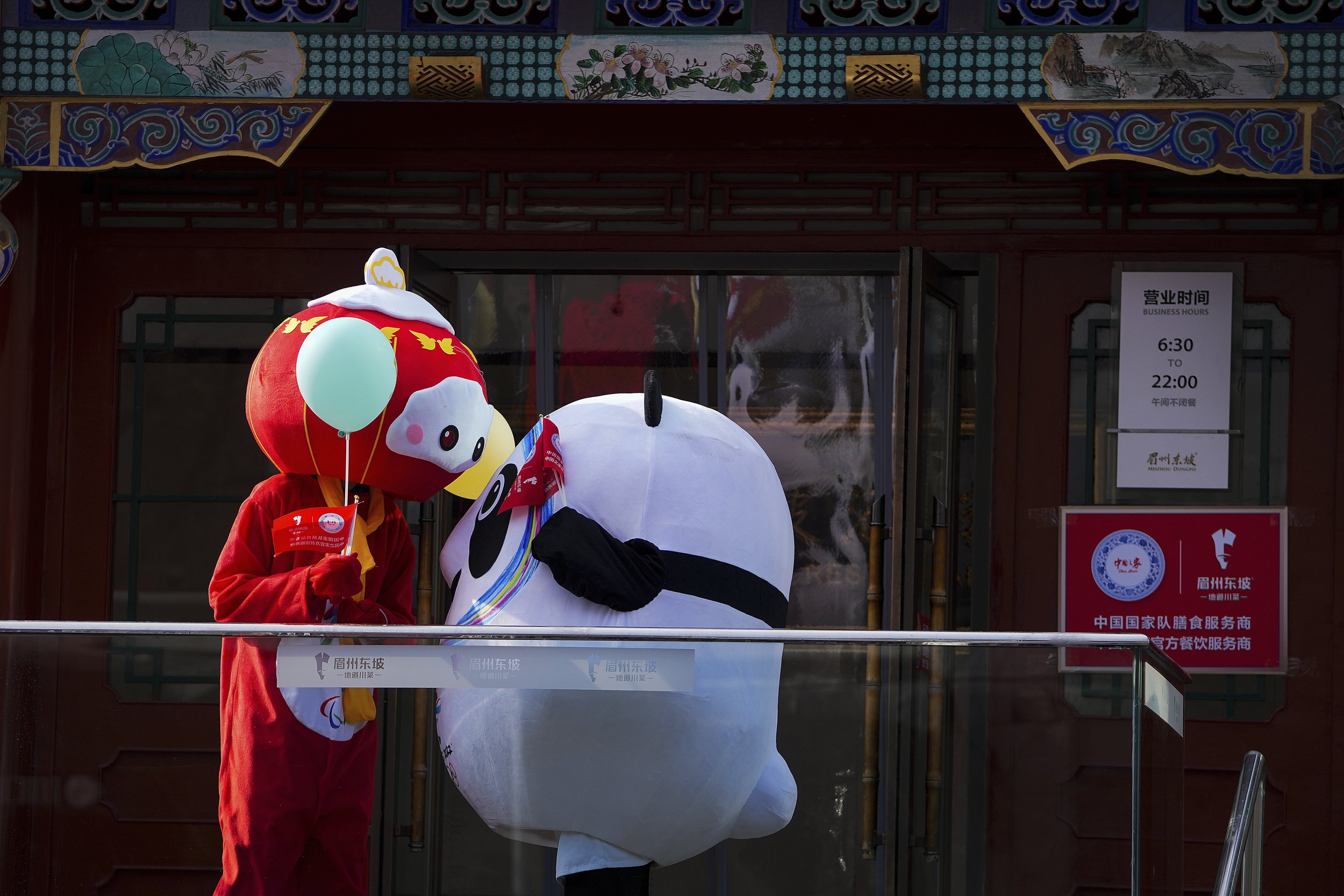  Workers wearing the mascot costumes of the Winter Olympics to attract customers chat outside a restaurant during the Lunar New Year Eve in Beijing, Jan. 31, 2022. (AP Photo/Andy Wong) 