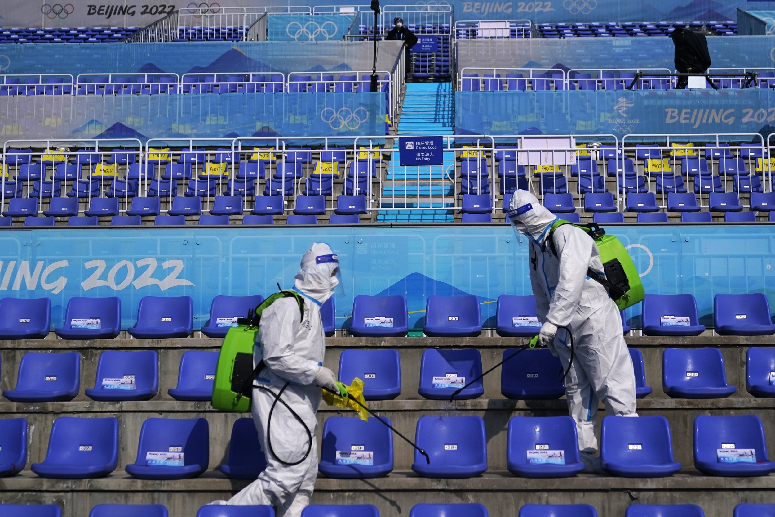  Workers in protective gear disinfect seats following the men's freestyle skiing big air finals of the 2022 Winter Olympics, Wednesday, Feb. 9, 2022, in Beijing. (AP Photo/Jae C. Hong) 