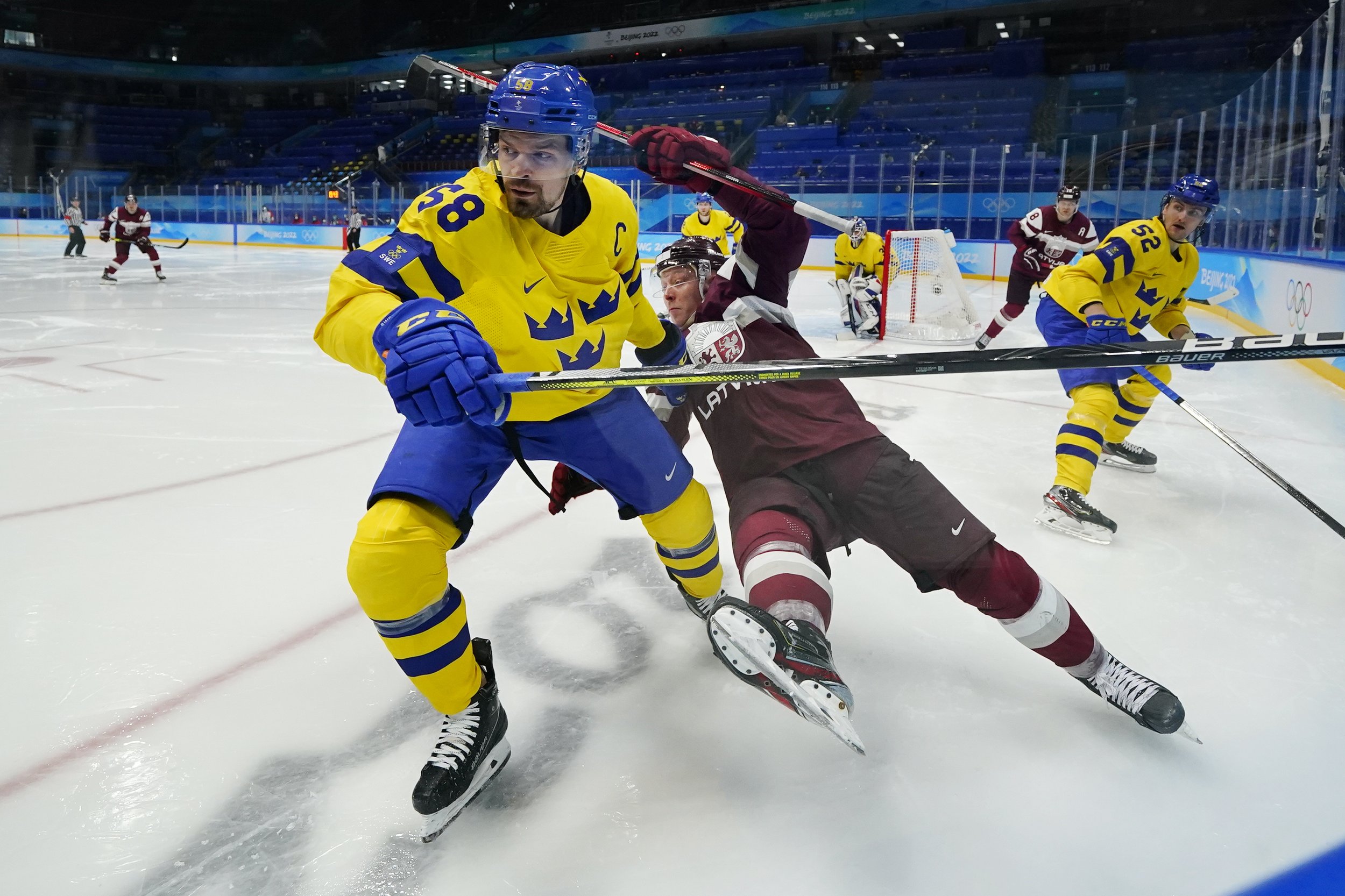  Sweden's Anton Lander (58) and Latvia's Ronalds Kenins (91) battle in the corner during a preliminary round men's hockey game at the 2022 Winter Olympics, Thursday, Feb. 10, 2022, in Beijing. (AP Photo/Matt Slocum) 