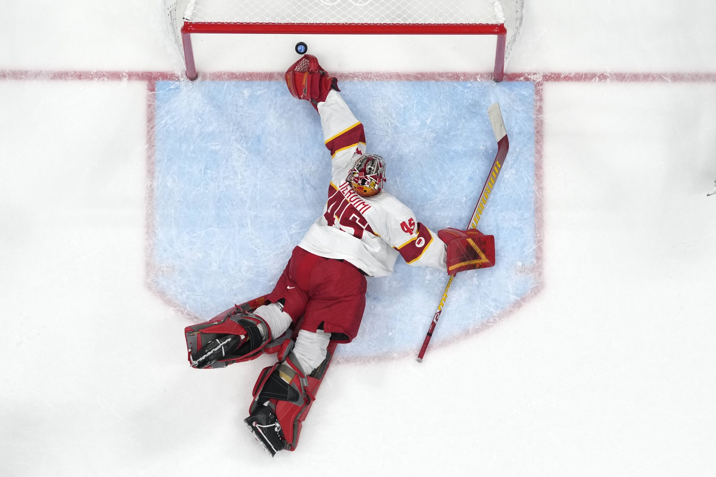  China goalkeeper Jieruimi Shimisi (Jeremy Smith) (45) reaches for a goal by United States' Brian Oneill during a preliminary round men's hockey game at the 2022 Winter Olympics, Thursday, Feb. 10, 2022, in Beijing. (AP Photo/Matt Slocum) 