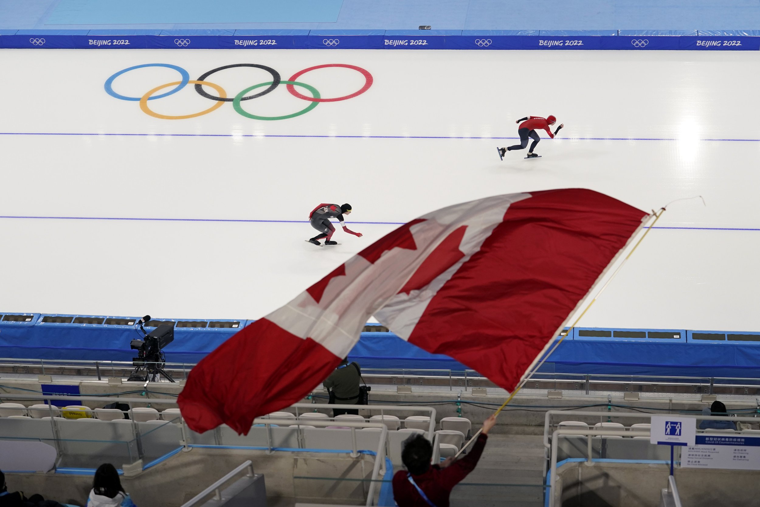  Isabelle Weidemann of Canada, let, competes against Ragne Wiklund of Norway, as a spectator waves a Canadian flag, during the women's speedskating 5,000-meter race at the 2022 Winter Olympics, Thursday, Feb. 10, 2022, in Beijing. (AP Photo/Ashley La