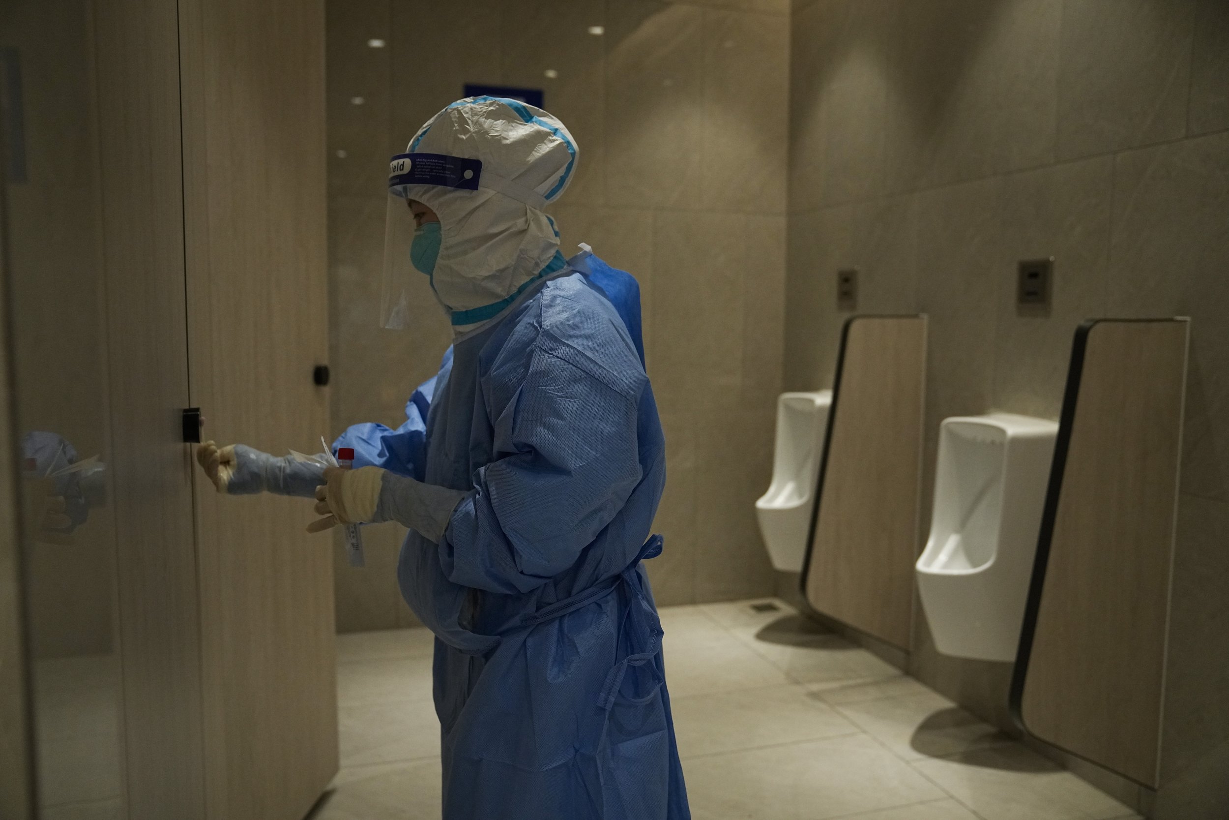  A medical worker collects a sample in a men's restroom for COVID testing in the main media center at the 2022 Winter Olympics, Friday, Feb. 11, 2022, in Beijing. (AP Photo/Jae C. Hong) 