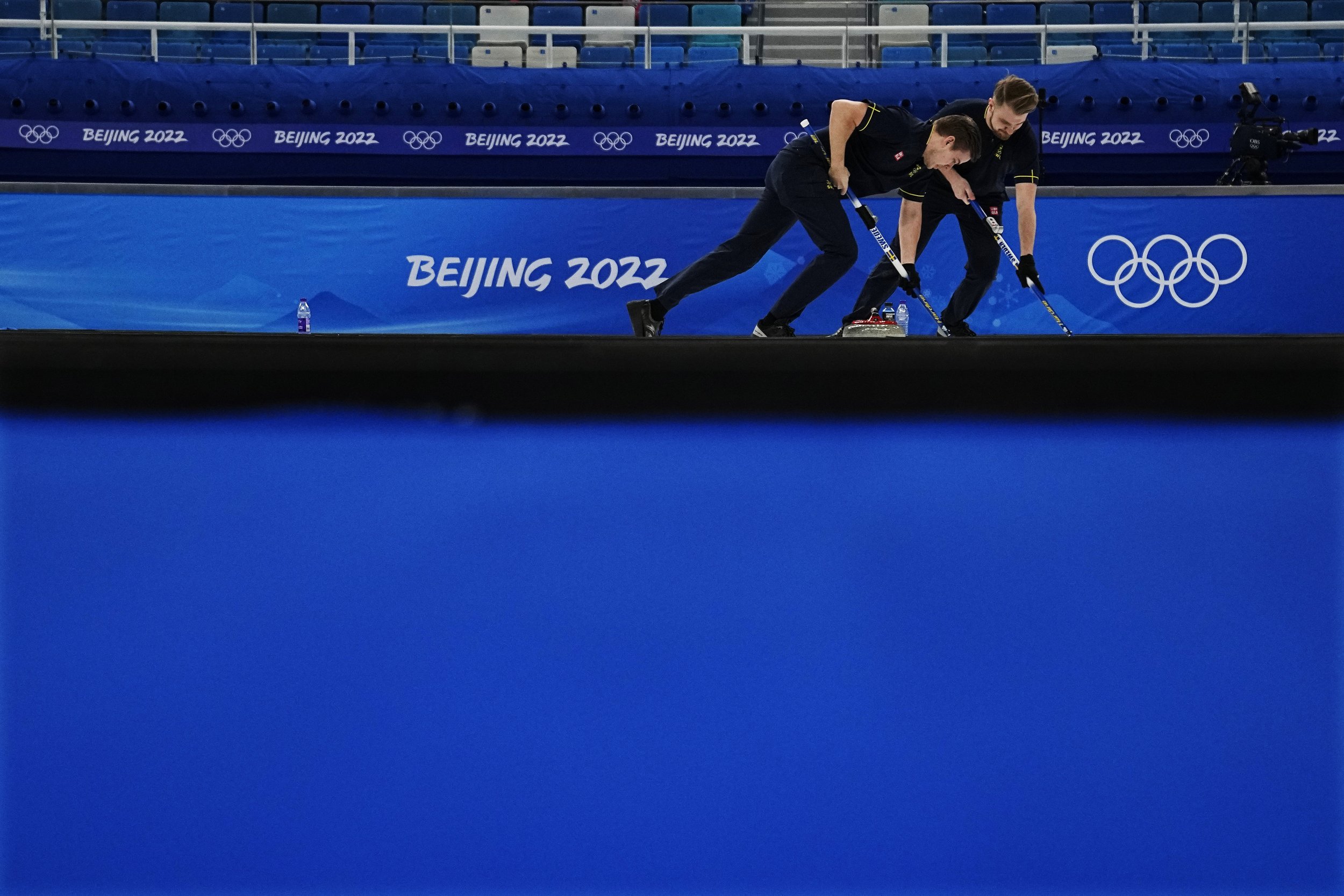  Team Sweden sweeps a rock during a men's curling match against Italy at the Beijing Winter Olympics Friday, Feb. 11, 2022, in Beijing. (AP Photo/Brynn Anderson) 