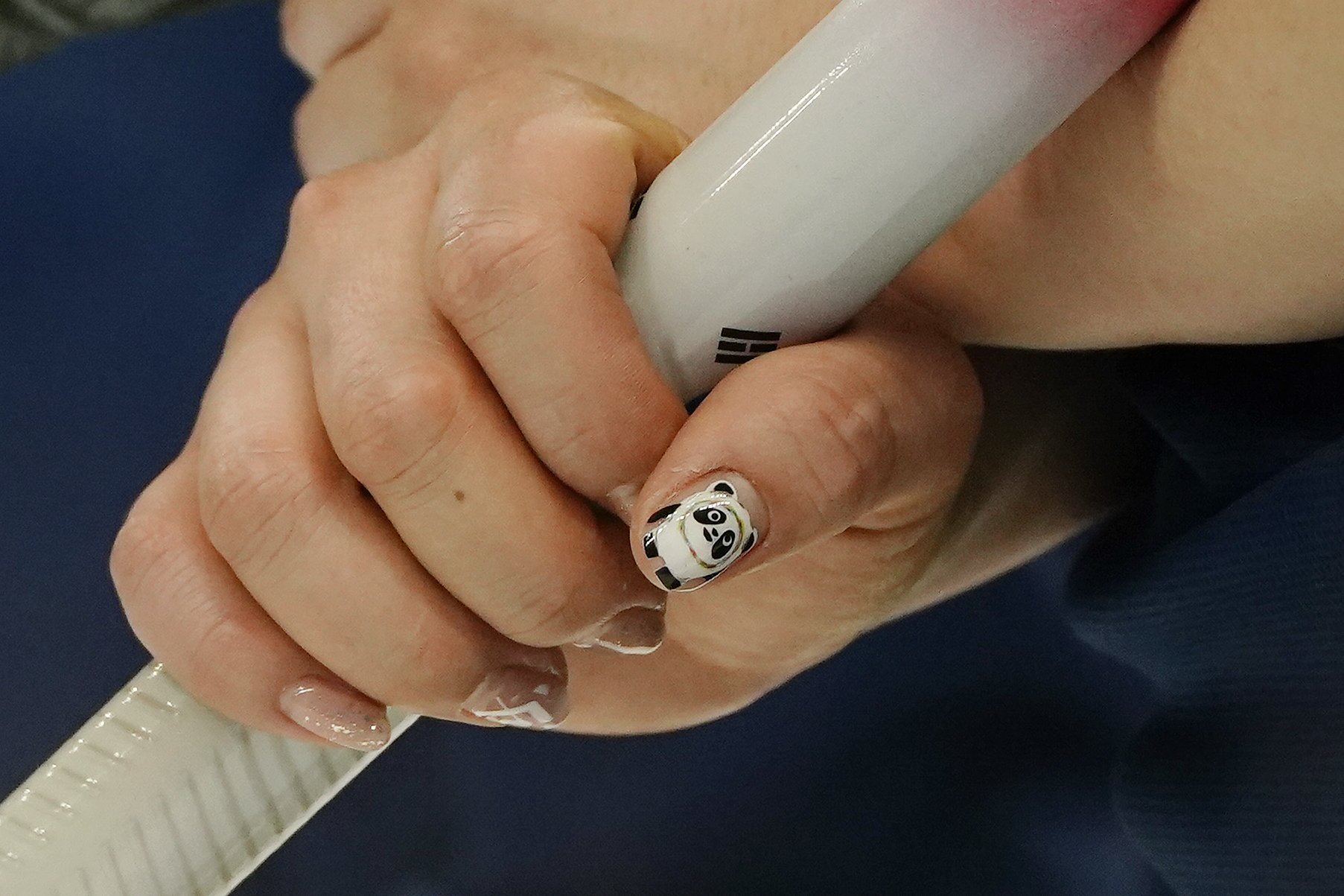  South Korea's Kim Kyeong-ae has Bing Dwen Dwen, the Beijing Winter Olympics mascot, on her nails during a women's curling match against Britain at the Beijing Winter Olympics Friday, Feb. 11, 2022, in Beijing. (AP Photo/Brynn Anderson) 