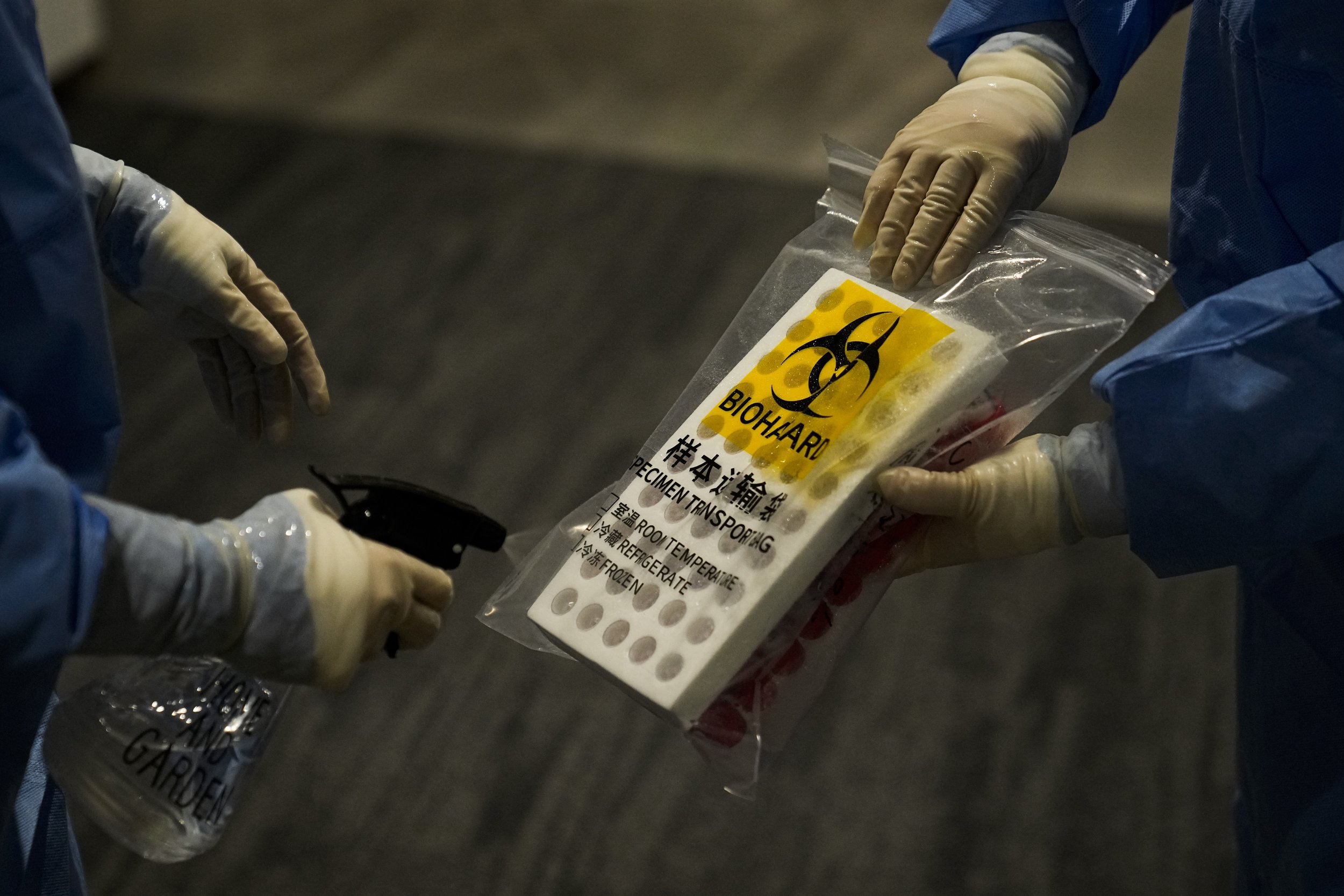  A medical worker sprays disinfectant on a plastic bag containing samples collected for COVID testing in the main media center at the 2022 Winter Olympics, Friday, Feb. 11, 2022, in Beijing. (AP Photo/Jae C. Hong) 