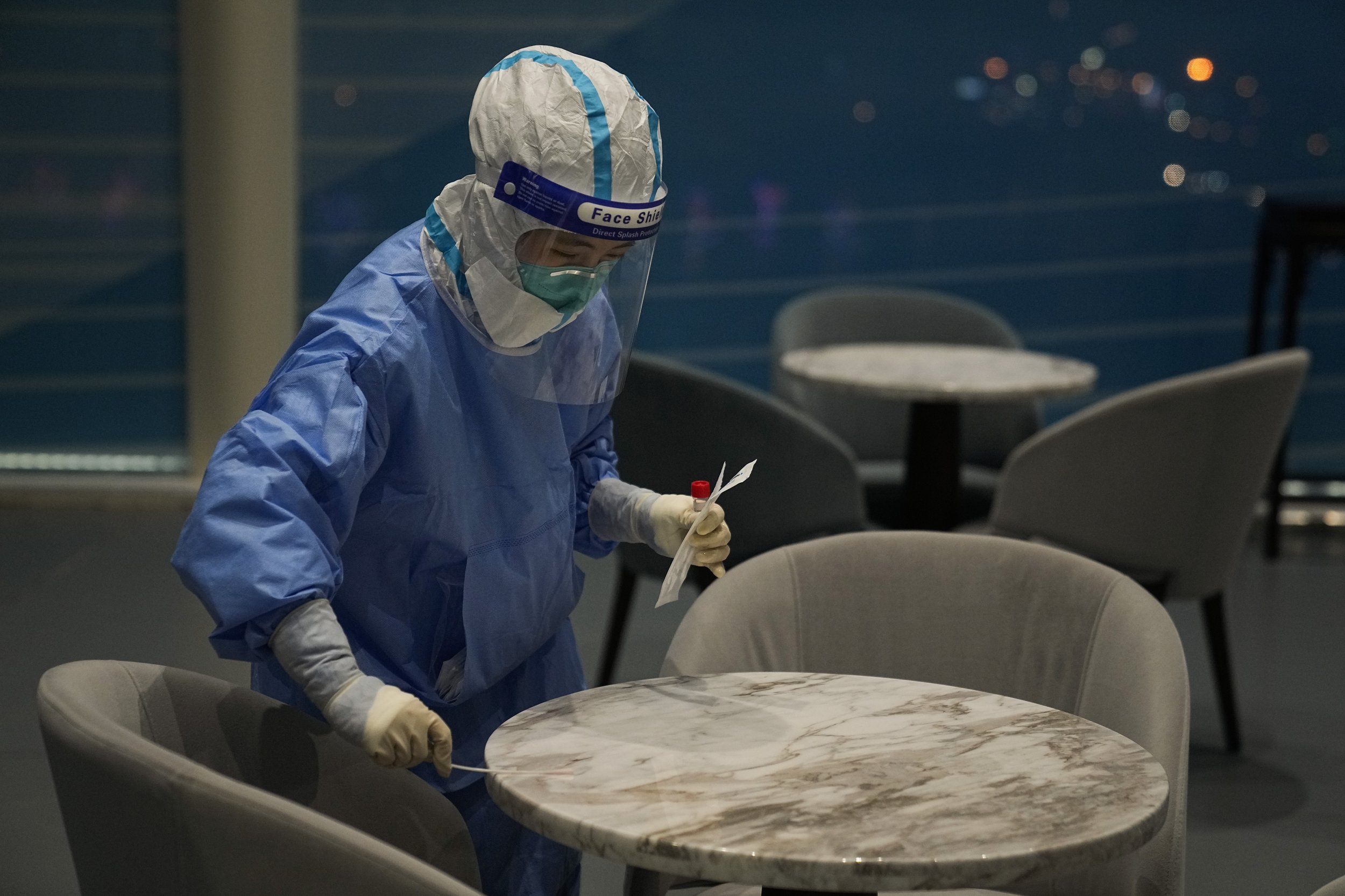  A medical worker collects a sample from a table for COVID testing in the lounge area of the main media center at the 2022 Winter Olympics, Friday, Feb. 11, 2022, in Beijing. (AP Photo/Jae C. Hong) 