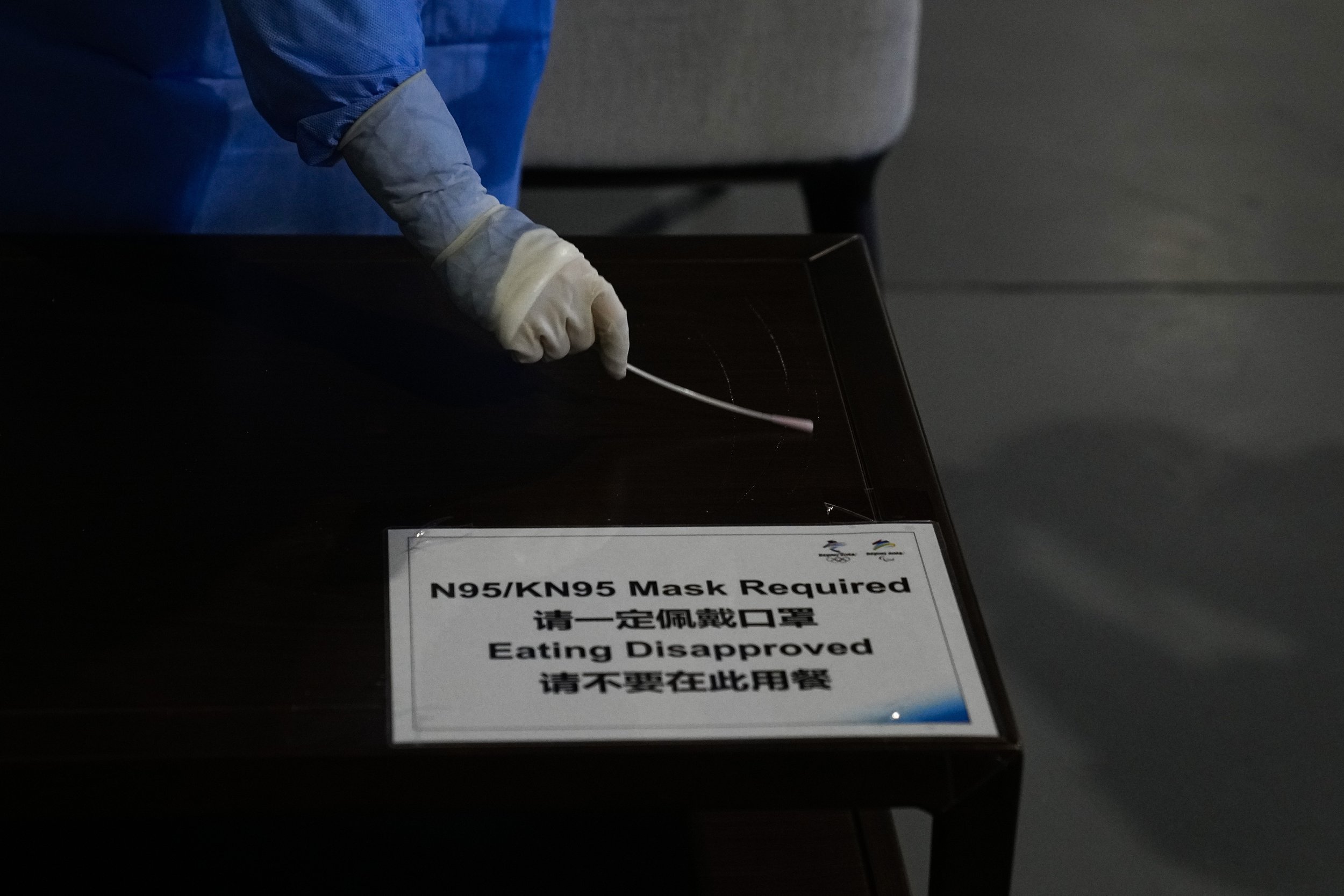  A medical worker collects a sample from a table to test for COVID-19 in the main media center at the 2022 Winter Olympics, Friday, Feb. 11, 2022, in Beijing. (AP Photo/Jae C. Hong) 