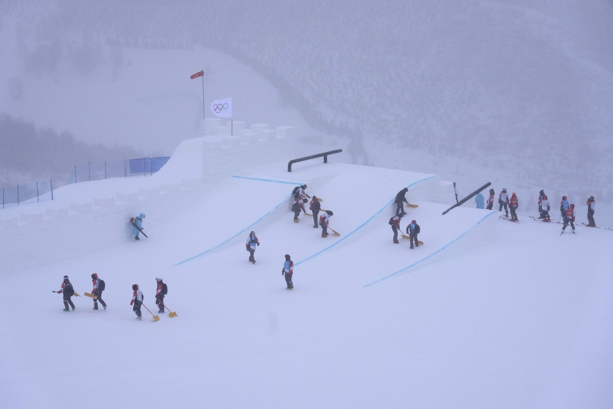  Volunteers clear the course as the start of the women's slopestyle qualification has been delayed due to a weather consition at the 2022 Winter Olympics, Sunday, Feb. 13, 2022, in Zhangjiakou, China. (AP Photo/Francisco Seco) 