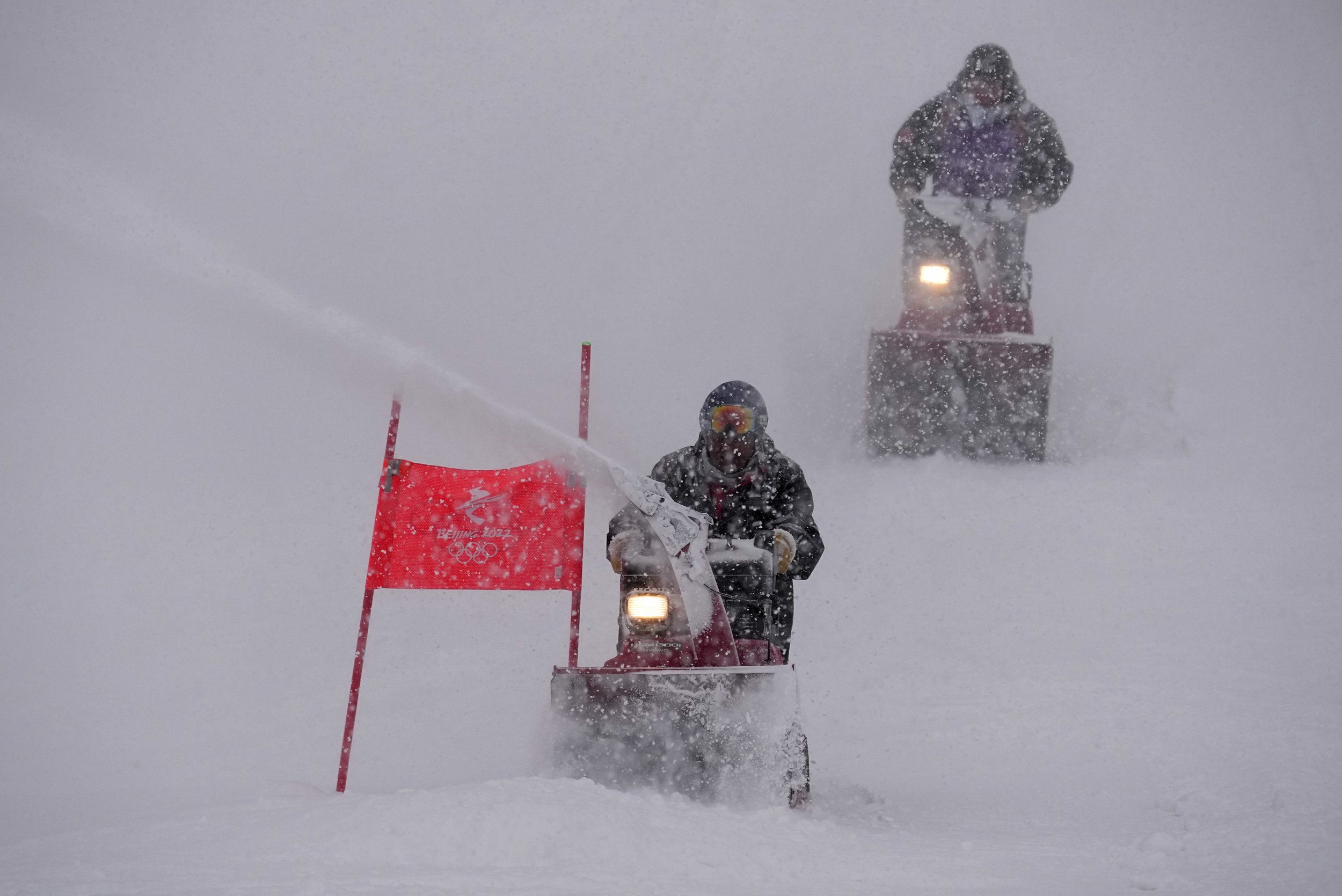  Course workers blow snow from the men's giant slalom course as the snow comes down at the alpine ski venue at the 2022 Winter Olympics, Sunday, Feb. 13, 2022, in the Yanqing district of Beijing. (AP Photo/Robert F. Bukaty) 