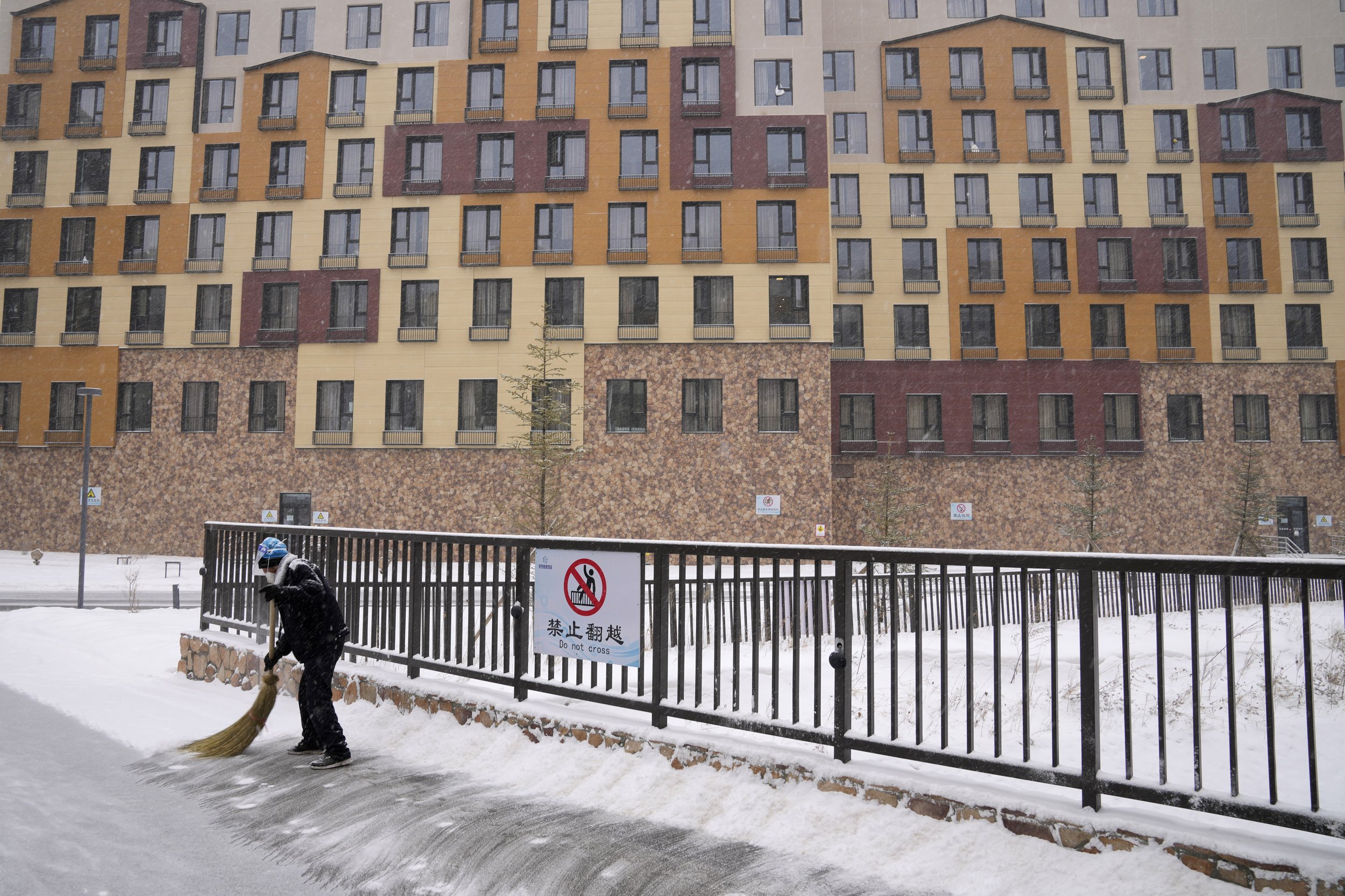  A worker sweeps away snow during a snowstorm at a hotel complex at the 2022 Winter Olympics, Sunday, Feb. 13, 2022, in Zhangjiakou, China. (AP Photo/Aaron Favila) 