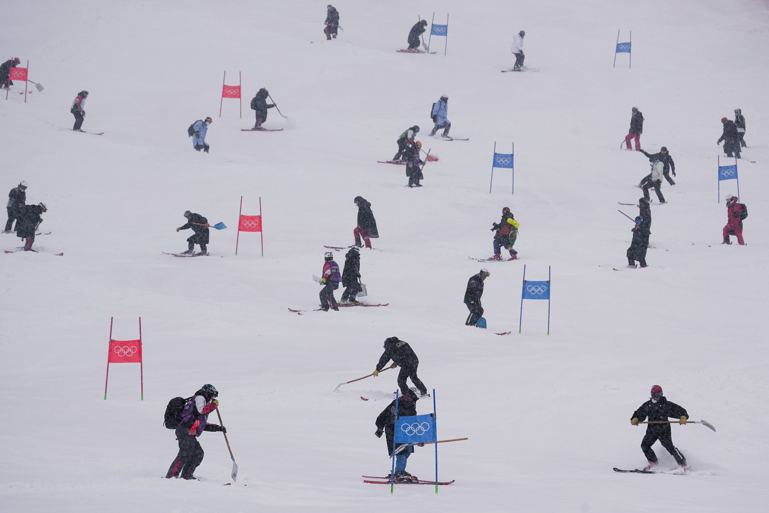 Workers clear snow from the course after the second run of the men's giant slalom was delayed due to a heavy snowfall at the 2022 Winter Olympics, Sunday, Feb. 13, 2022, in the Yanqing district of Beijing. (AP Photo/Robert F. Bukaty) 