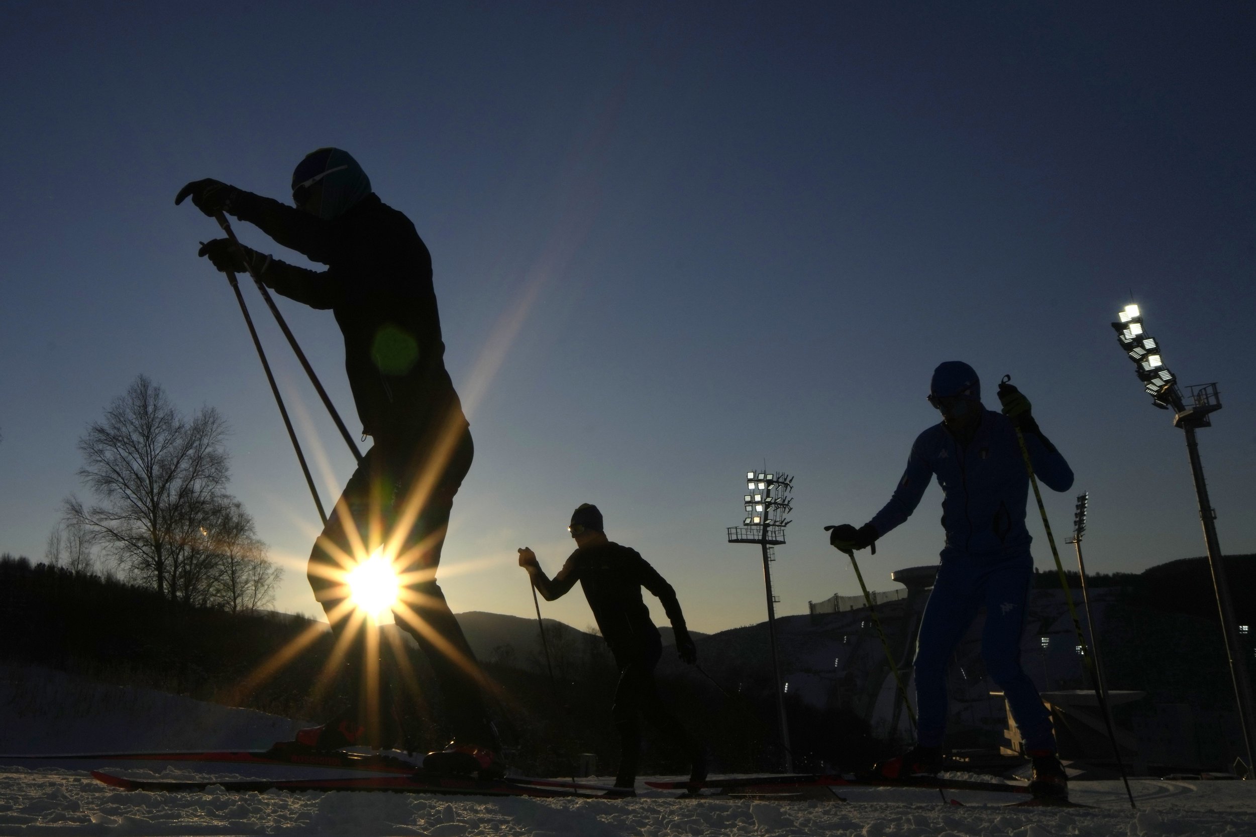  Biathletes train as the sun sets during a biathlon training session during the 2022 Winter Olympics, in Zhangjiakou, China, Monday, Feb. 14, 2022. (AP Photo/Kirsty Wigglesworth) 