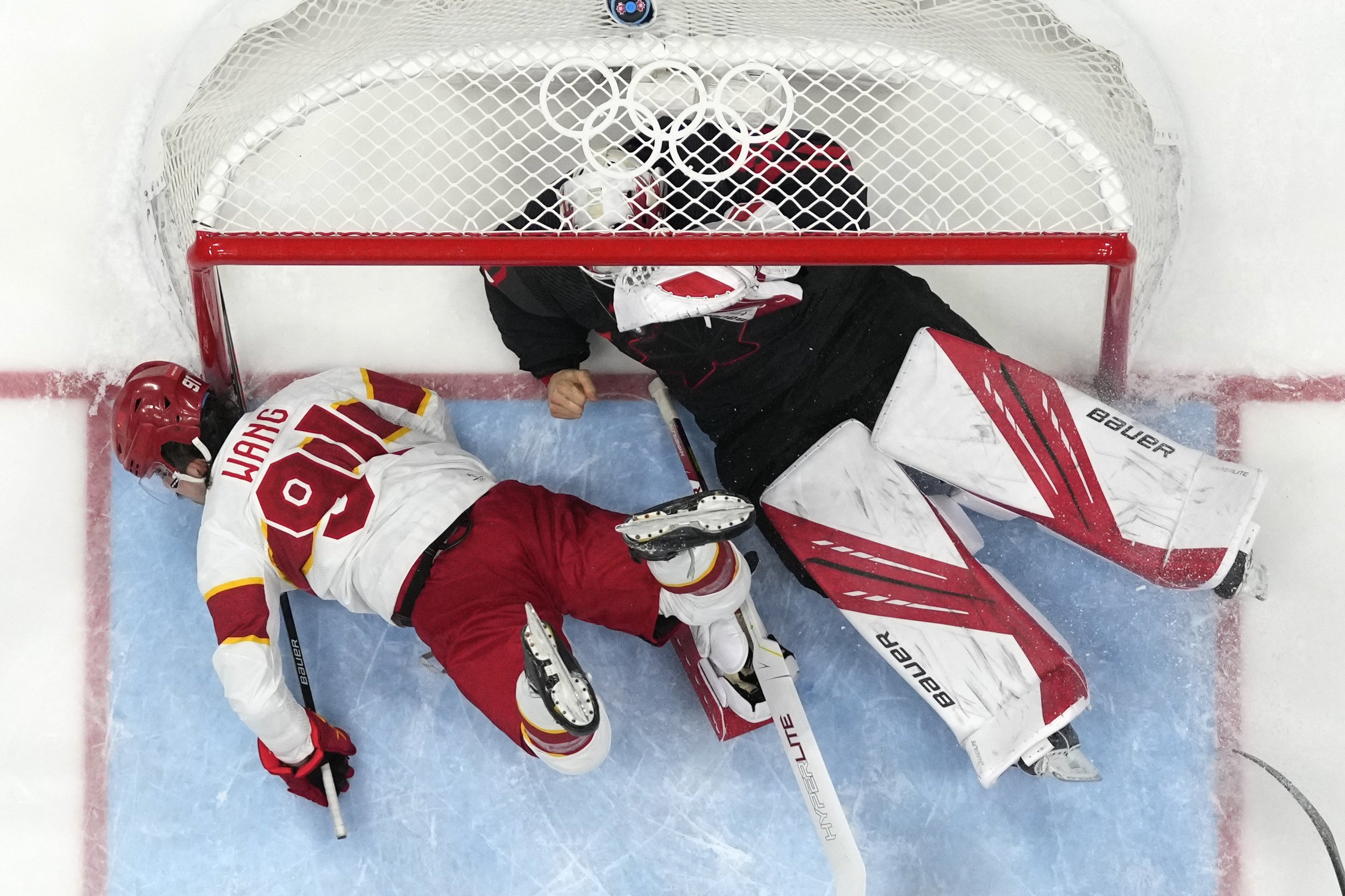  China's Wang Taile (Tyler Wong) (91) hits the post as he collides with Canada goalkeeper Matt Tomkins during a men's qualification round hockey game at the 2022 Winter Olympics, Tuesday, Feb. 15, 2022, in Beijing. (AP Photo/Matt Slocum) 