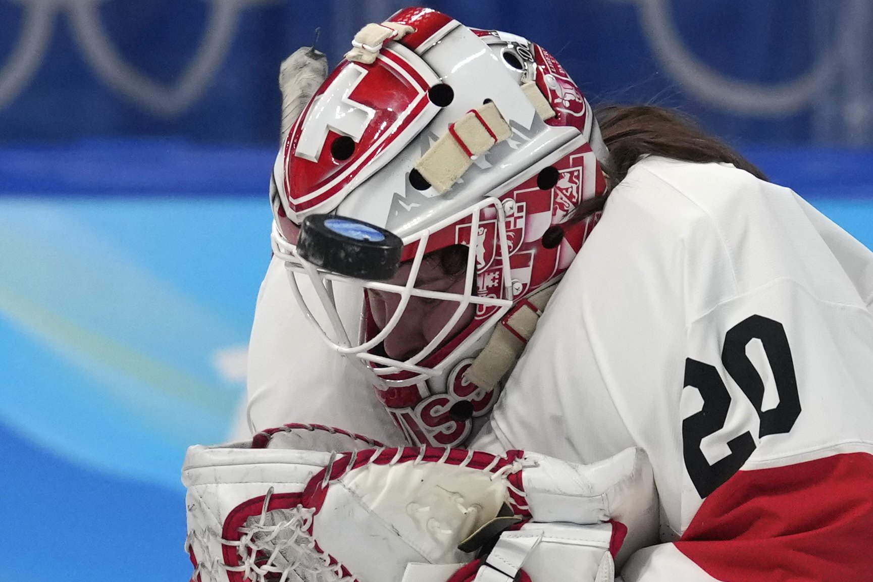  The puck hits the mask of Switzerland goalkeeper Andrea Braendli during the women's bronze medal hockey game against Finland at the 2022 Winter Olympics, Wednesday, Feb. 16, 2022, in Beijing. (AP Photo/Petr David Josek) 