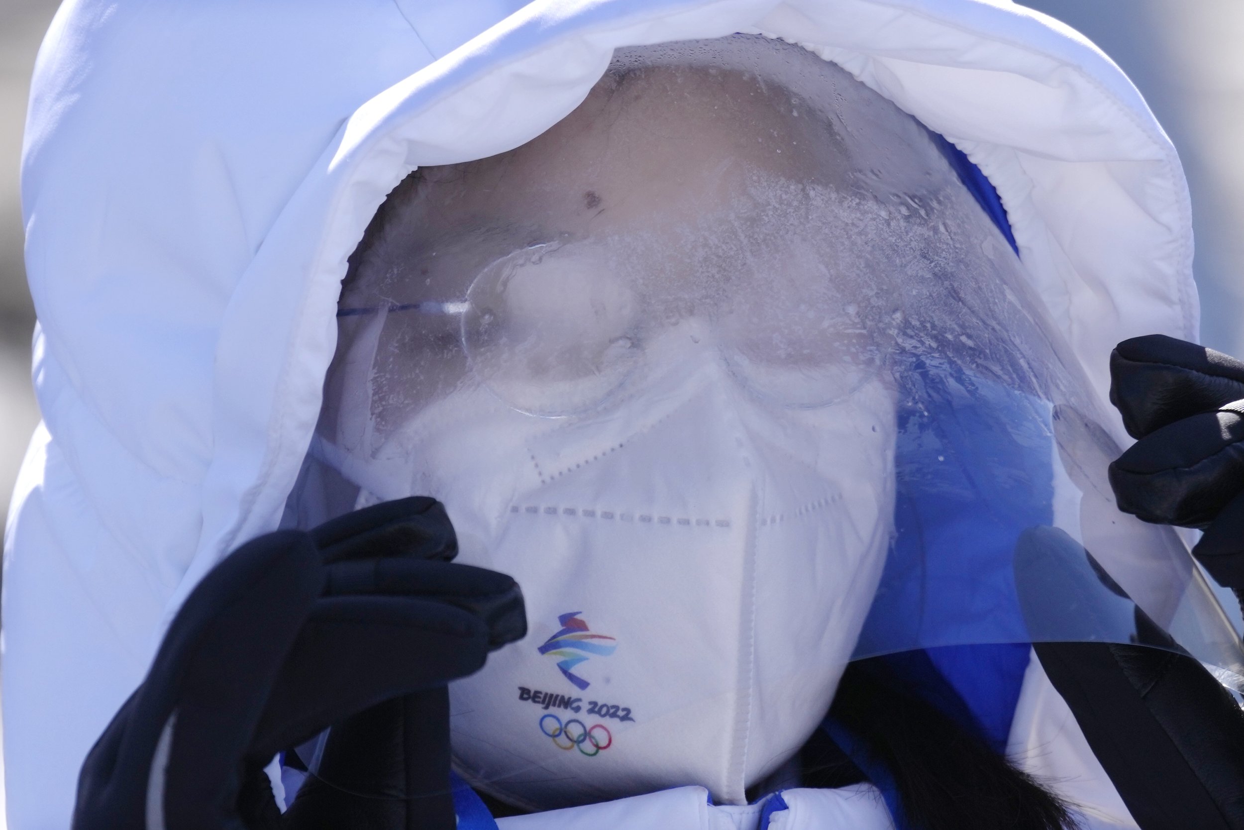  A volunteer lifts her frost covered mask at the National Biathlon Center during a practice session for the 2022 Winter Olympics, Thursday, Feb. 3, 2022, in Zhangjiakou, China. (AP Photo/Kirsty Wigglesworth) 