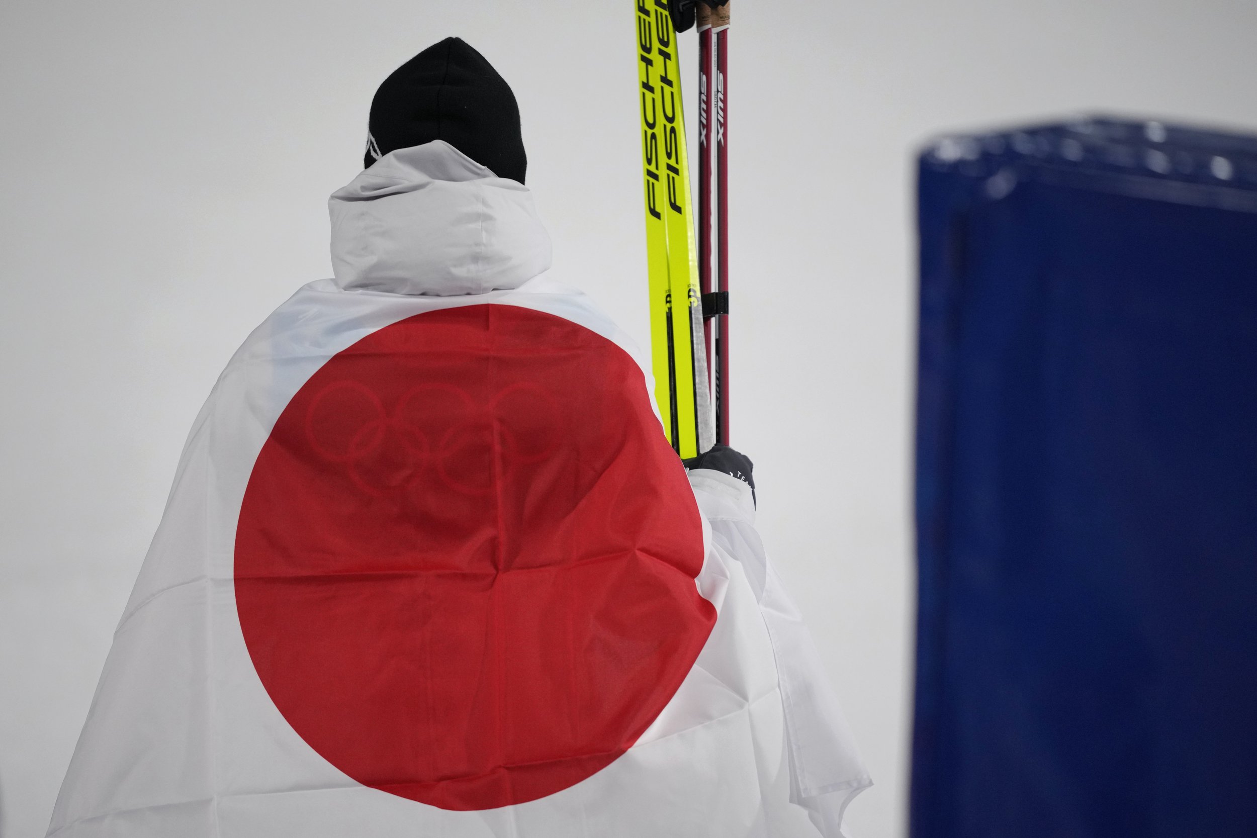  Bronze medal finisher Japan's Akito Watabe wraps himself in a flag during a venue ceremony after the cross-country skiing portion of the individual Gundersen large hill/10km competition at the 2022 Winter Olympics, Tuesday, Feb. 15, 2022, in Zhangji