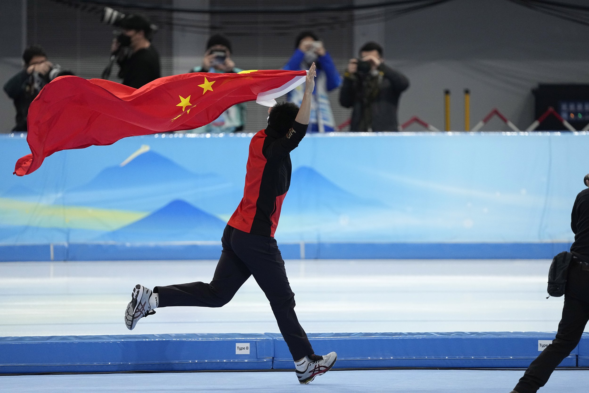  Gao Tingyu of China carries his country's flag after winning the gold medal and setting an Olympic record in the men's speedskating 500-meter race at the 2022 Winter Olympics, Saturday, Feb. 12, 2022, in Beijing. (AP Photo/Ashley Landis) 