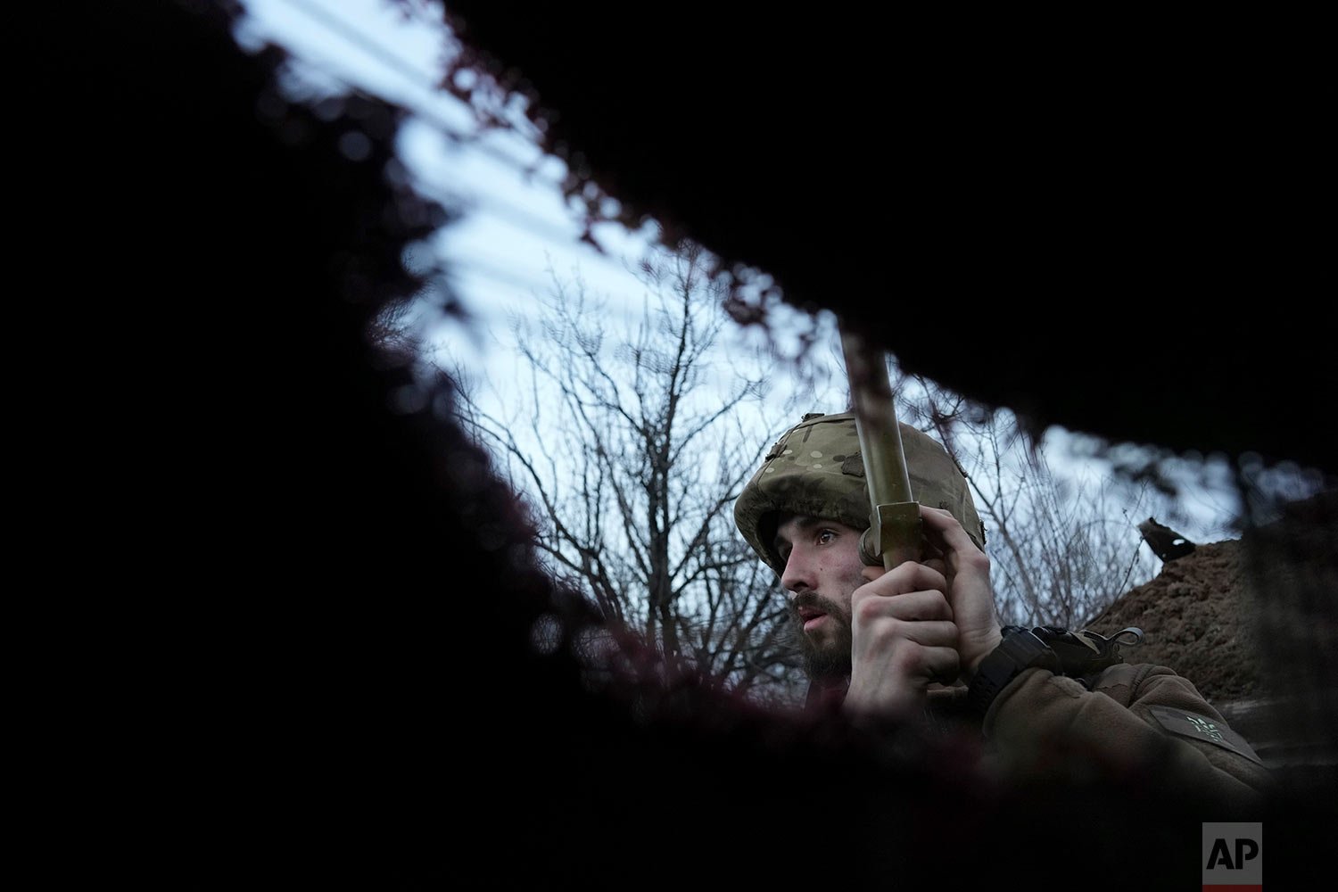  A Ukrainian service member listens to artillery shots standing in a trench on a position at the line of separation between Ukraine-held territory and rebel-held territory near Zolote, Ukraine, late Saturday, Feb. 19, 2022. (AP Photo/Evgeniy Maloletk