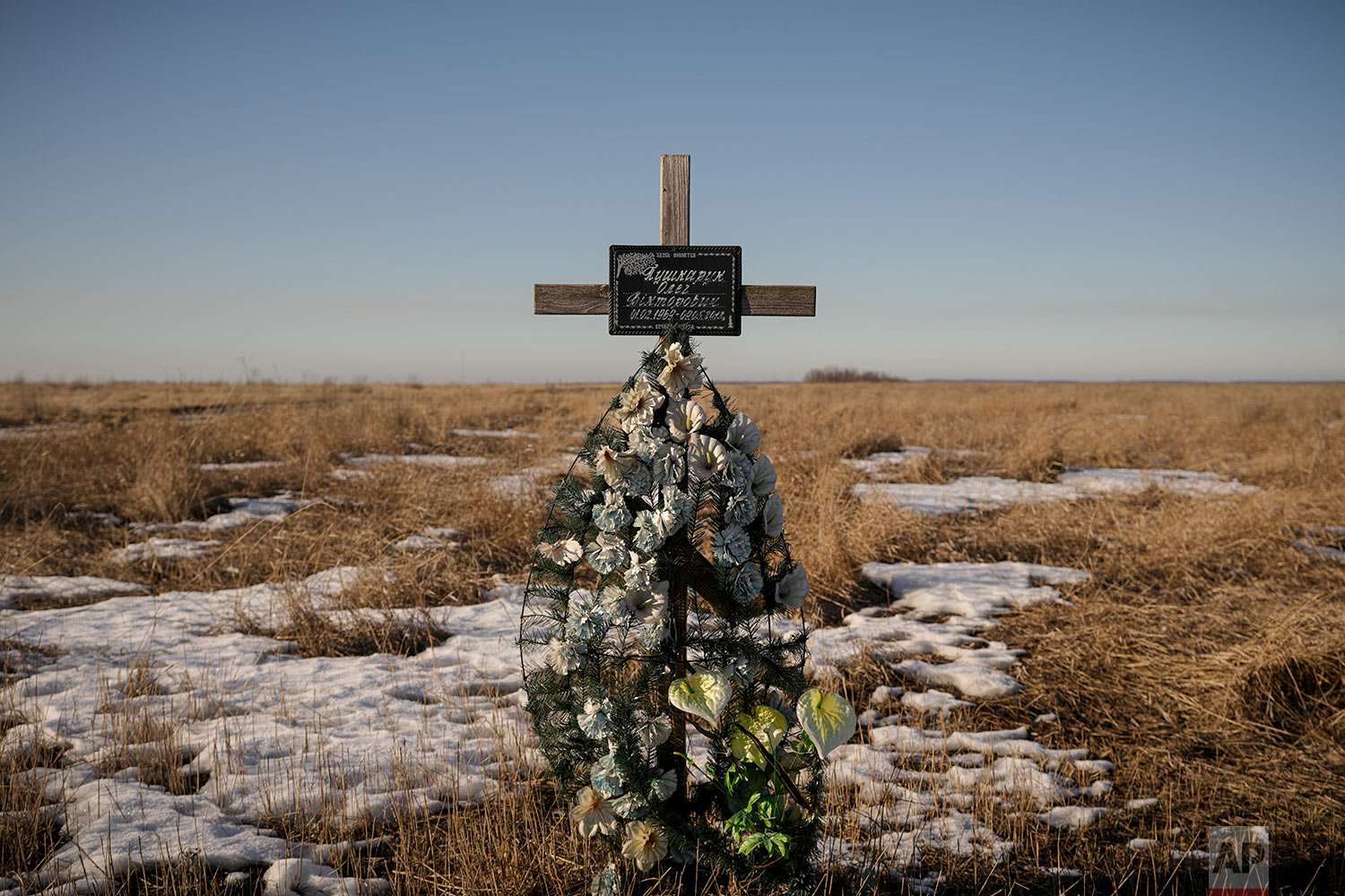  A cross in memory of a Ukrainian soldier is placed in a field near the place he was killed on in 2018, at a front line position outside Popasna, Luhansk region, eastern Ukraine, Monday, Feb. 14, 2022. (AP Photo/Vadim Ghirda) 