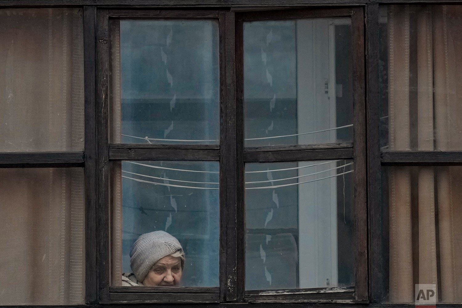  A woman looks out of the window of a balcony in Sievierodonetsk, in the Luhansk region, eastern Ukraine, Friday, Feb. 18, 2022. (AP Photo/Vadim Ghirda) 