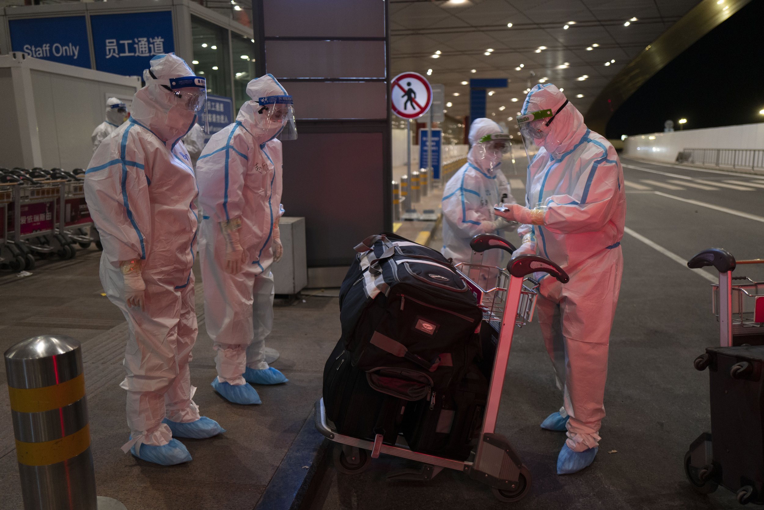  Airport workers assist with luggage at the Beijing Capital International Airport at the 2022 Winter Olympics, Monday, Feb. 21, 2022, in Beijing. (AP Photo/Jae C. Hong) 