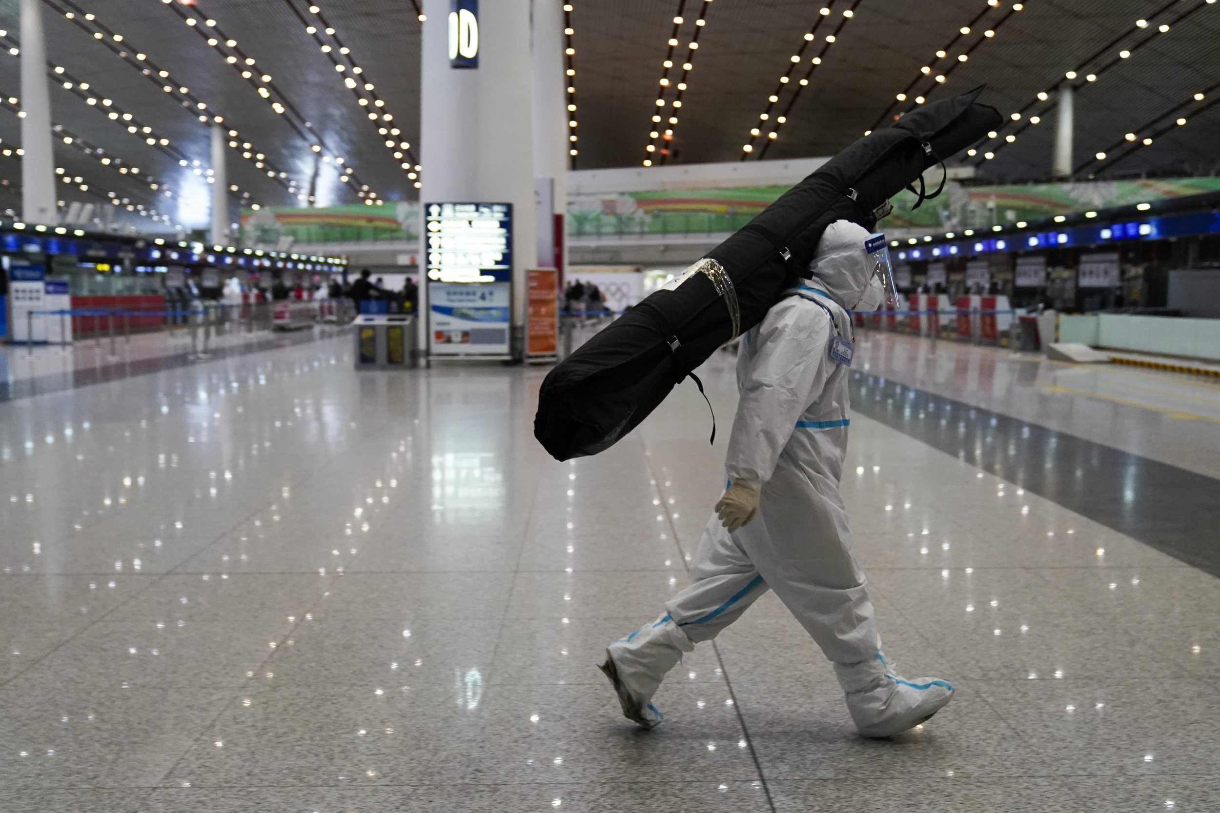  A volunteer carries a passenger's luggage at Beijing Capital International Airport after the 2022 Winter Olympics, Sunday, Feb. 20, 2022, in Beijing. (AP Photo/Ashley Landis) 