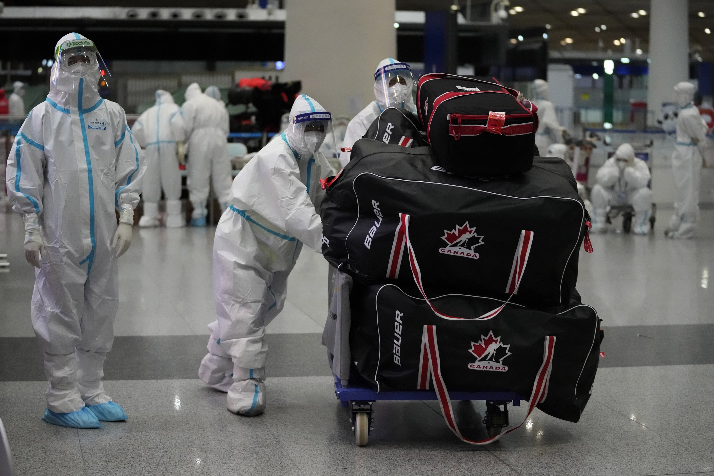  Olympic workers in protective clothing help travelers at Beijing Capital International Airport after the 2022 Winter Olympics, Monday, Feb. 21, 2022, in Beijing, China. (AP Photo/Frank Augstein) 