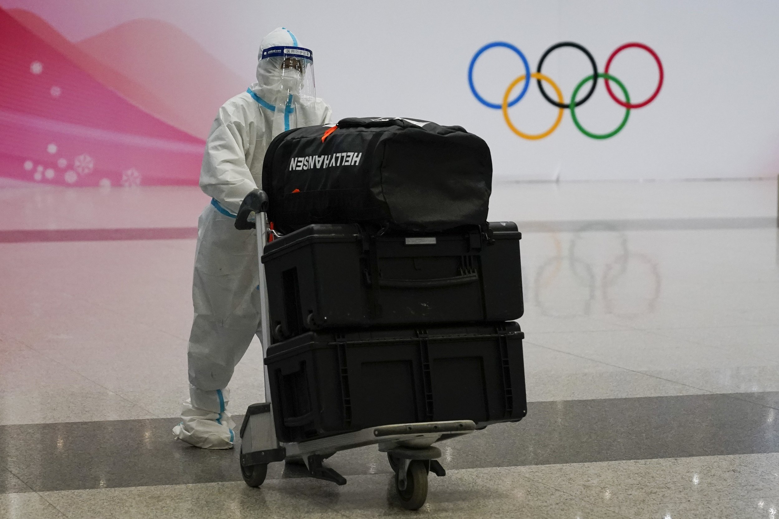  A volunteer moves a passenger's baggage at Beijing Capital International Airport after the conclusion of the 2022 Winter Olympics, Sunday, Feb. 20, 2022, in Beijing. (AP Photo/Ashley Landis) 