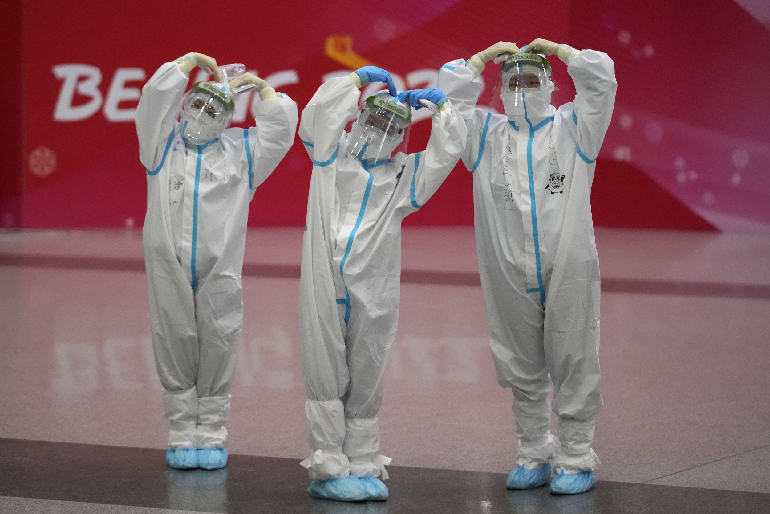  Olympic workers in protective clothing pose for a picture at the Beijing Capital International Airport after the 2022 Winter Olympics, Monday, Feb. 21, 2022, in Beijing, China. (AP Photo/Frank Augstein) 