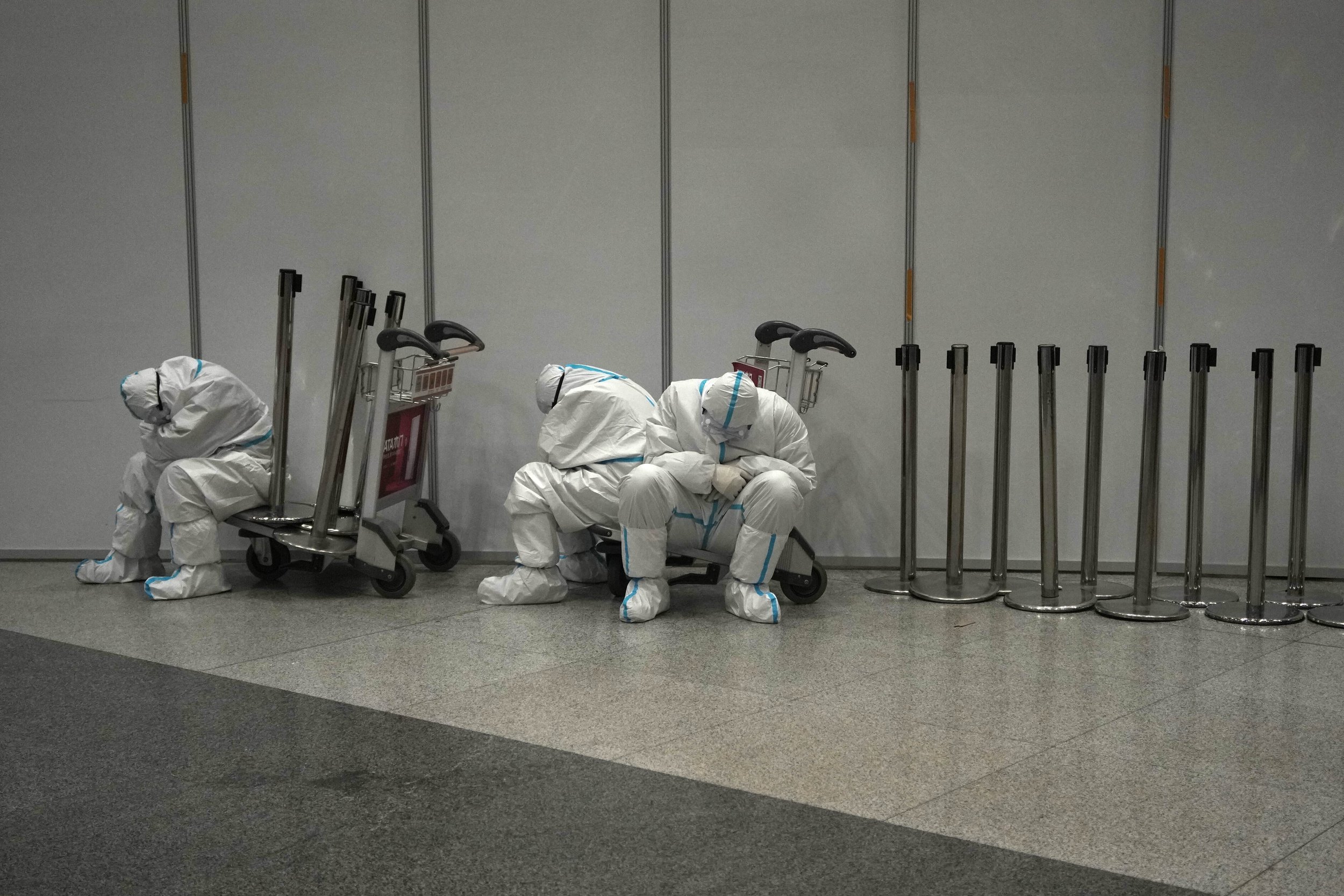  Olympic workers in protective clothing rest after they helped travelers at the Beijing Capital International Airport after the 2022 Winter Olympics, Monday, Feb. 21, 2022, in Beijing, China. (AP Photo/Alessandra Tarantino) 