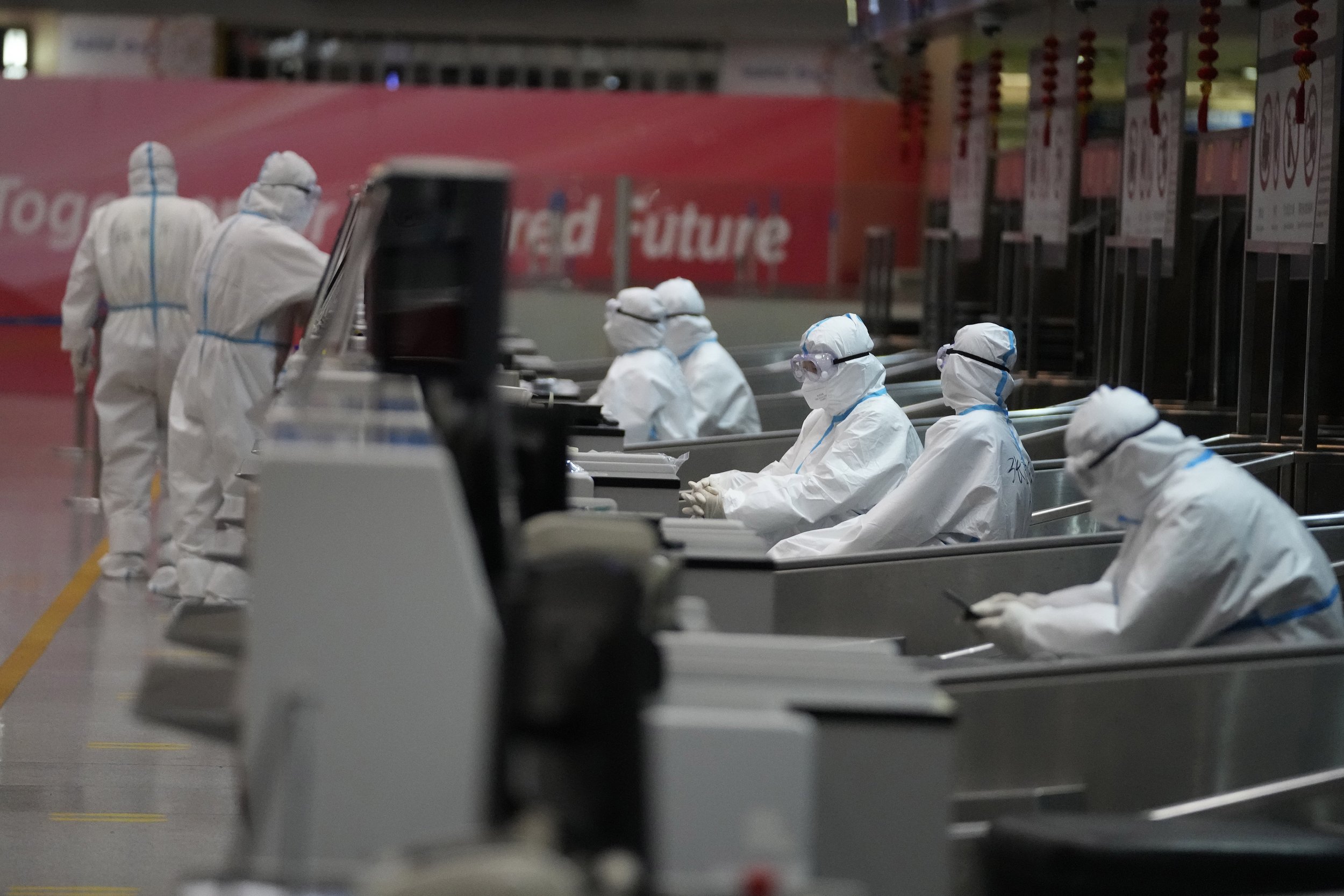  Olympic workers in protective clothing help travelers at the Beijing Capital International airport after the 2022 Winter Olympics, Monday, Feb. 21, 2022, in Beijing, China. (AP Photo/Frank Augstein) 