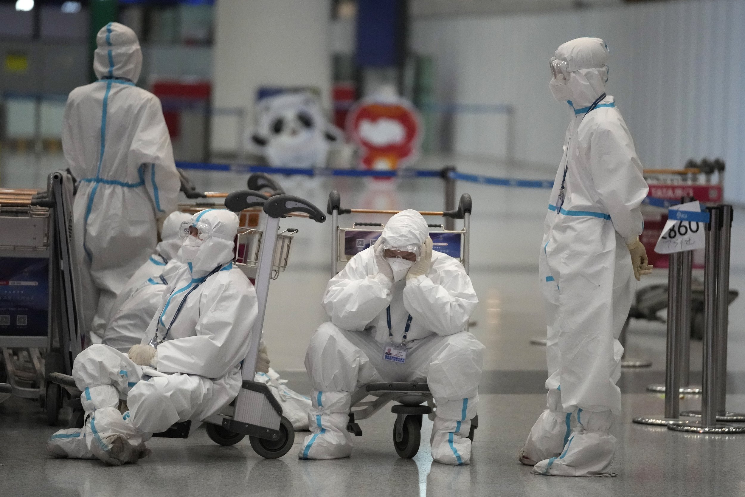  Olympic workers in protective clothing take a rest after helping travelers at the Beijing Capital International Airport after the 2022 Winter Olympics, Monday, Feb. 21, 2022, in Beijing, China. (AP Photo/Frank Augstein) 