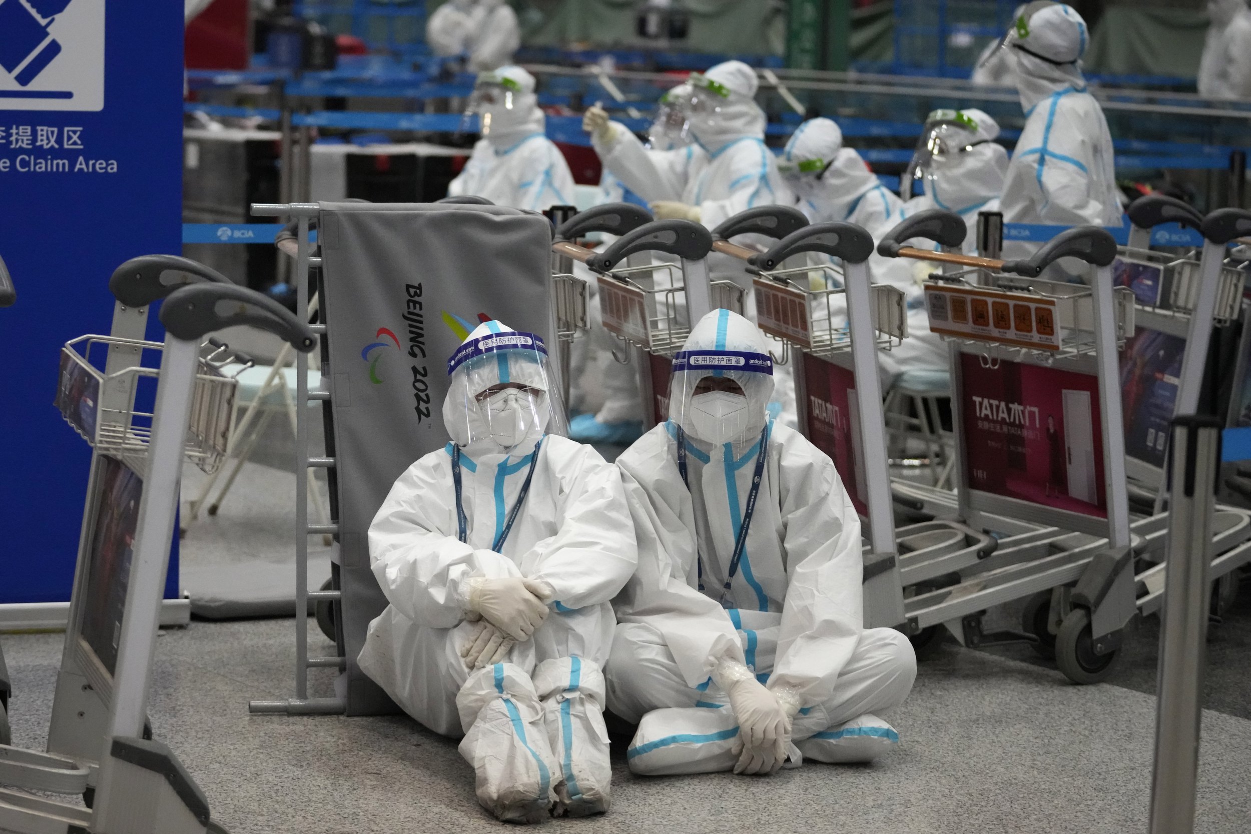  Olympic workers in protective clothing rest after they helped travelers at the Beijing Capital International airport after the 2022 Winter Olympics, Monday, Feb. 21, 2022, in Beijing, China. (AP Photo/Frank Augstein) 