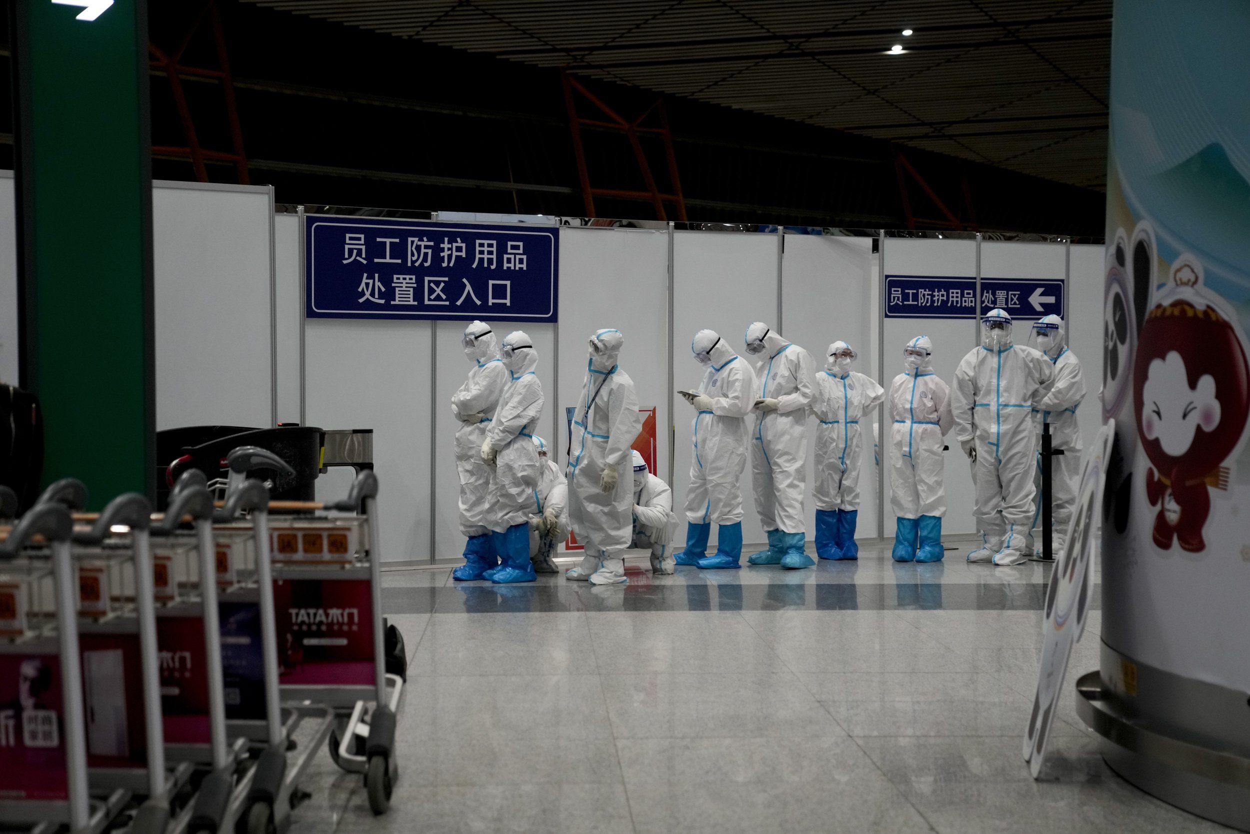  Olympic workers in protective clothing stand at the Beijing Capital International Airport after the 2022 Winter Olympics, Monday, Feb. 21, 2022, in Beijing. (AP Photo/Natacha Pisarenko) 