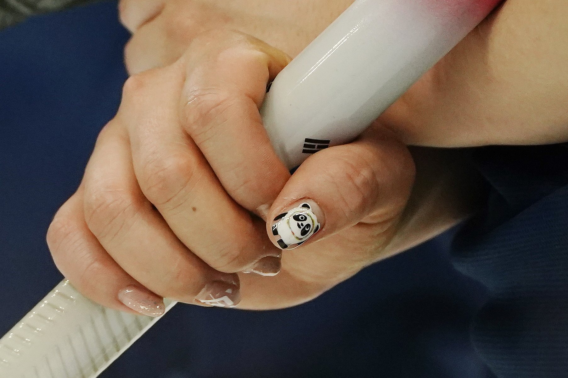  South Korea's Kim Kyeong-ae has Bing Dwen Dwen, the Olympics mascot, on her nails during a women's curling match against Britain at the Beijing Winter Olympics Friday, Feb. 11, 2022, in Beijing. (AP Photo/Brynn Anderson) 