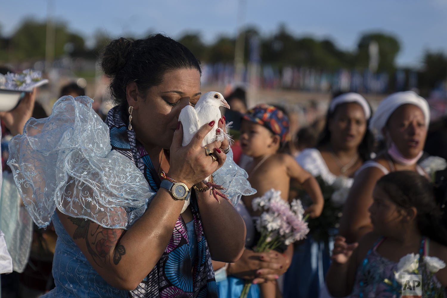  A woman kisses a pigeon during a ritual for the African sea goddess Yemanja on the beach in Montevideo, Uruguay, Feb. 2, 2022. Worshippers gather at the beach on her feast day, bringing candles, flowers, honey and fruit to honor her. (AP Photo/Matil