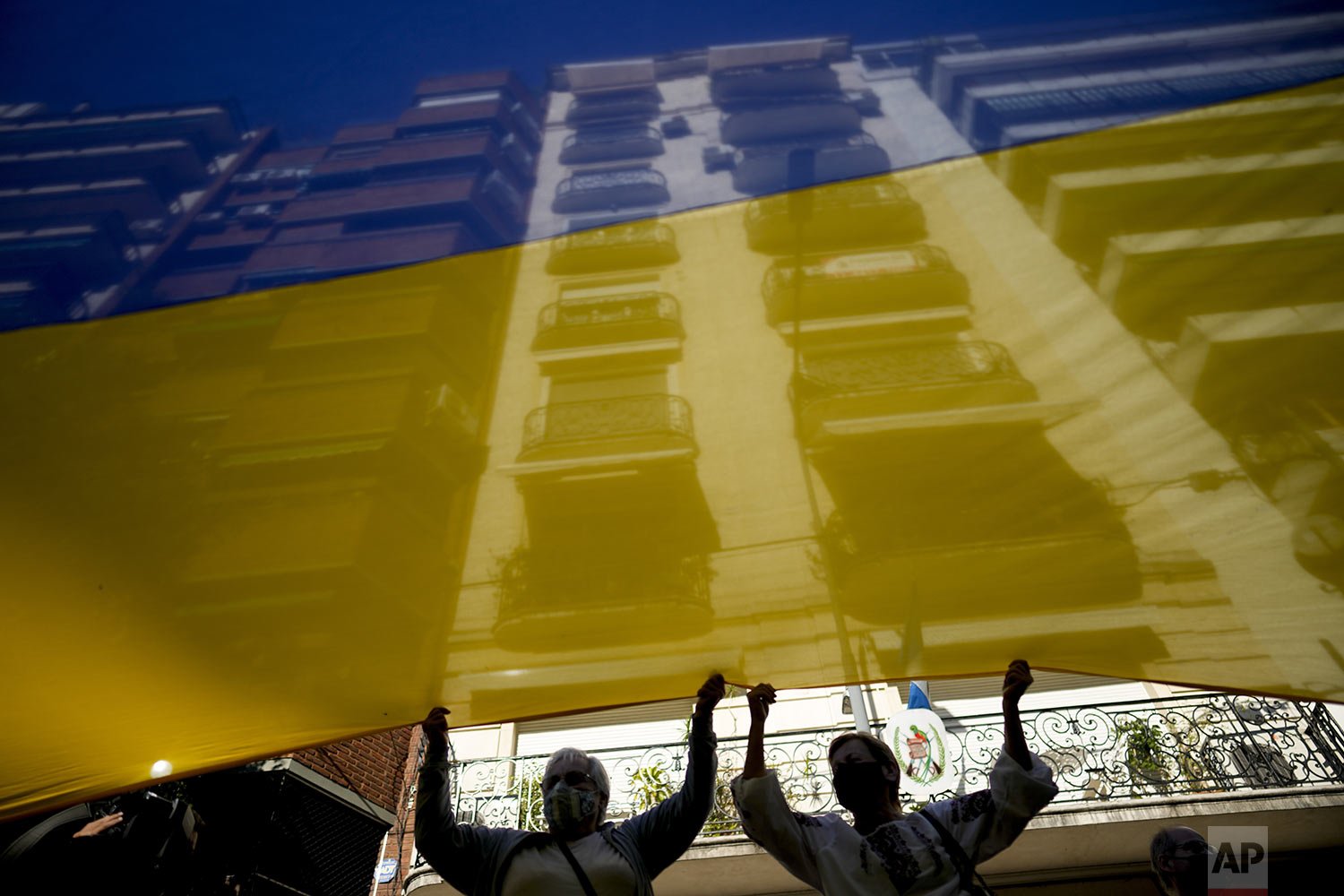  Women help display a Ukrainian flag as they protest against Russia's invasion of Ukraine, in Buenos Aires, Argentina, Feb. 25, 2022. (AP Photo'/Natacha Pisarenko) 