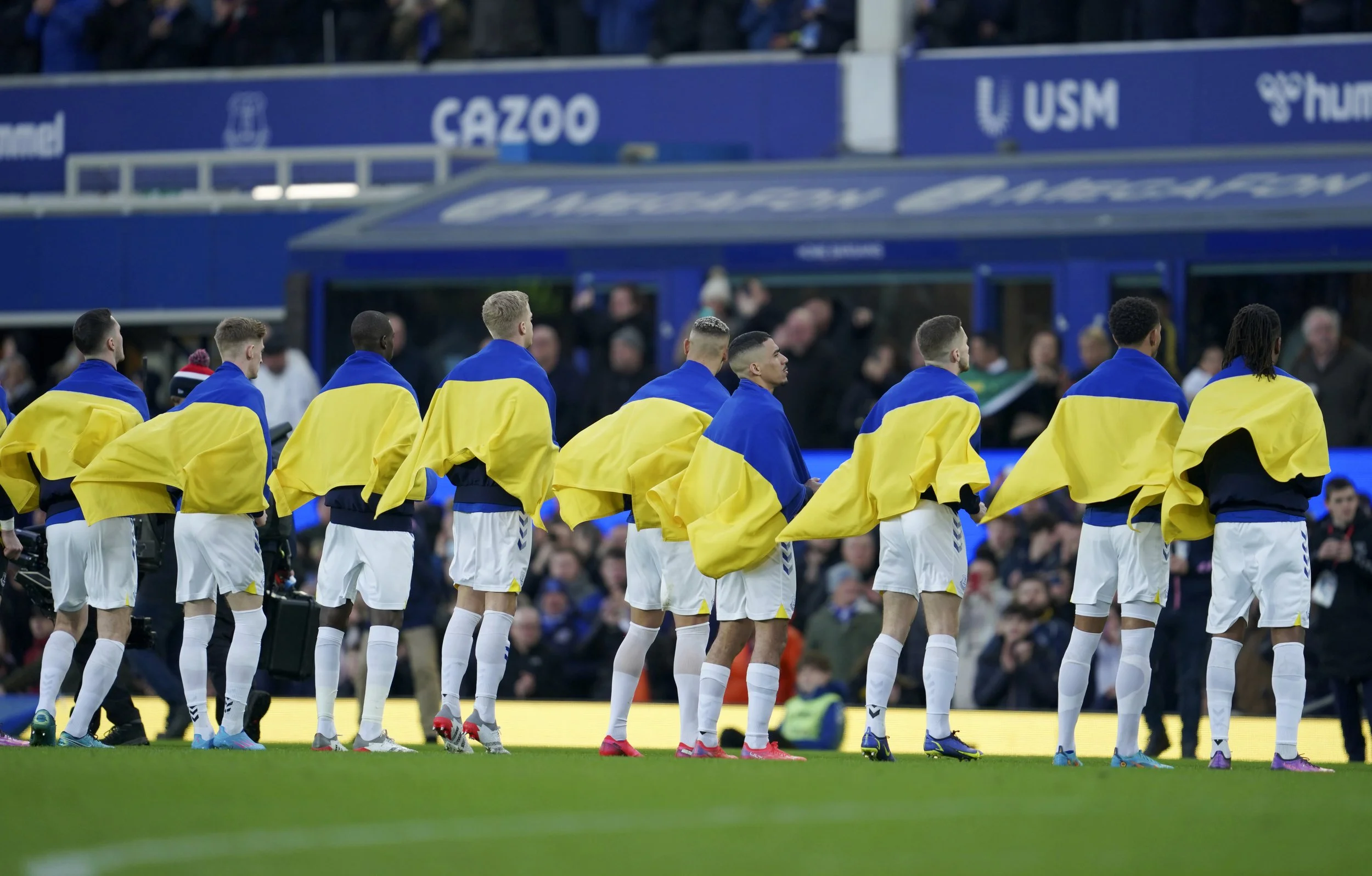  Everton players hold Ukrainian flags before the English Premier League soccer match between Everton and Manchester City at Goodison Park in Liverpool, England, Saturday, Feb. 26, 2022. (AP Photo/Jon Super) 