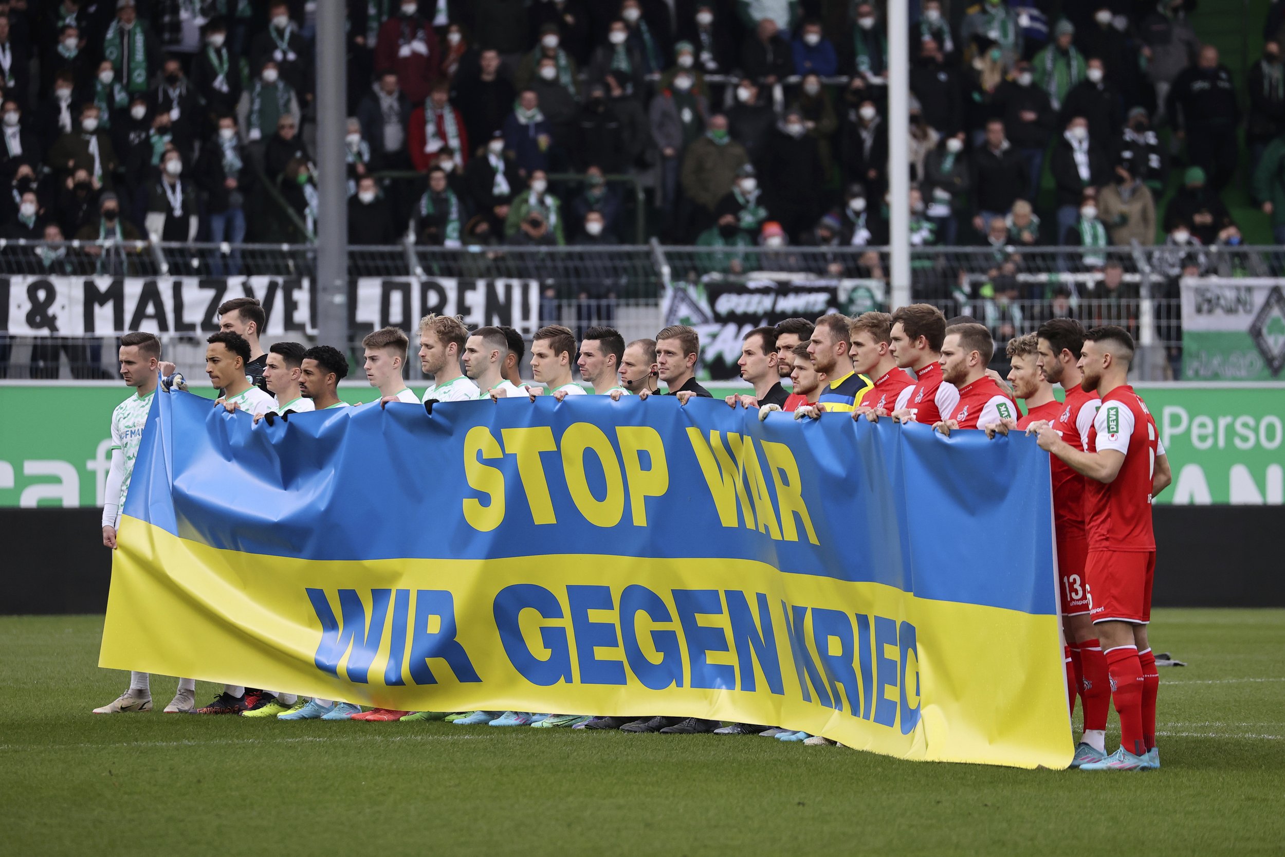  At the start of the match, the players of both teams hold a Ukrainian flag with the inscription "Stop War. We against war." prior the Bundesliga soccer match between Greuther Fuerth and 1. FC Cologne in Fuerth, Germany, Feb. 26, 2022. (Daniel Karman